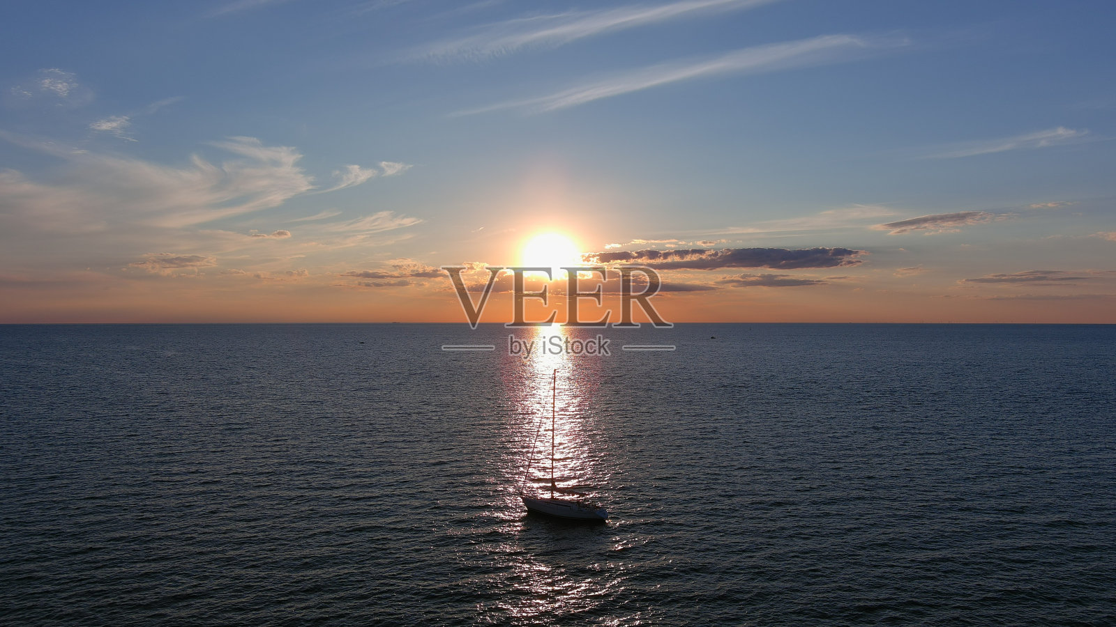 航拍中高角度的水面上绚丽的夕阳，帆船在阳光下照片摄影图片