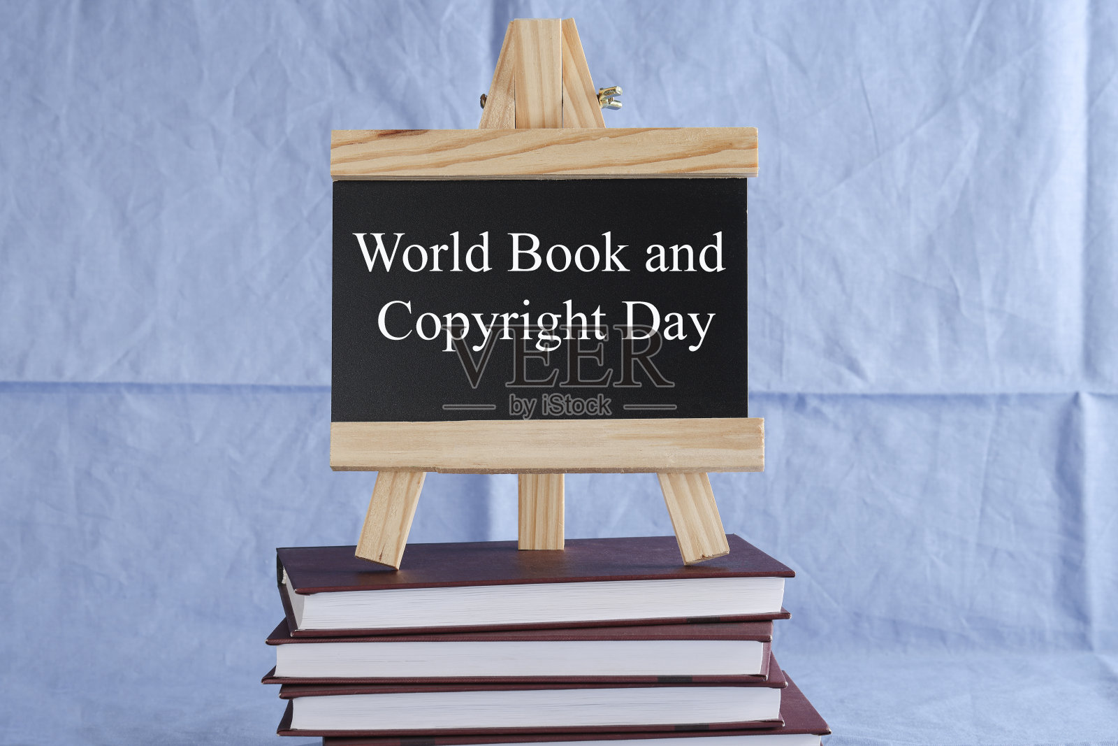 世界图书日和版权日写在蓝色背景的一摞书上的黑板上。图书假期，教育理念照片摄影图片
