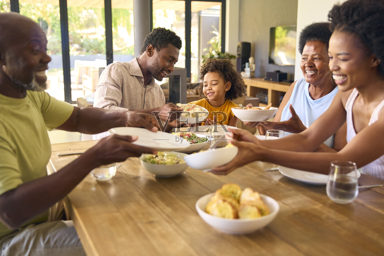 几代同堂的家庭围坐在餐桌旁，为家里的饭菜上菜照片摄影图片