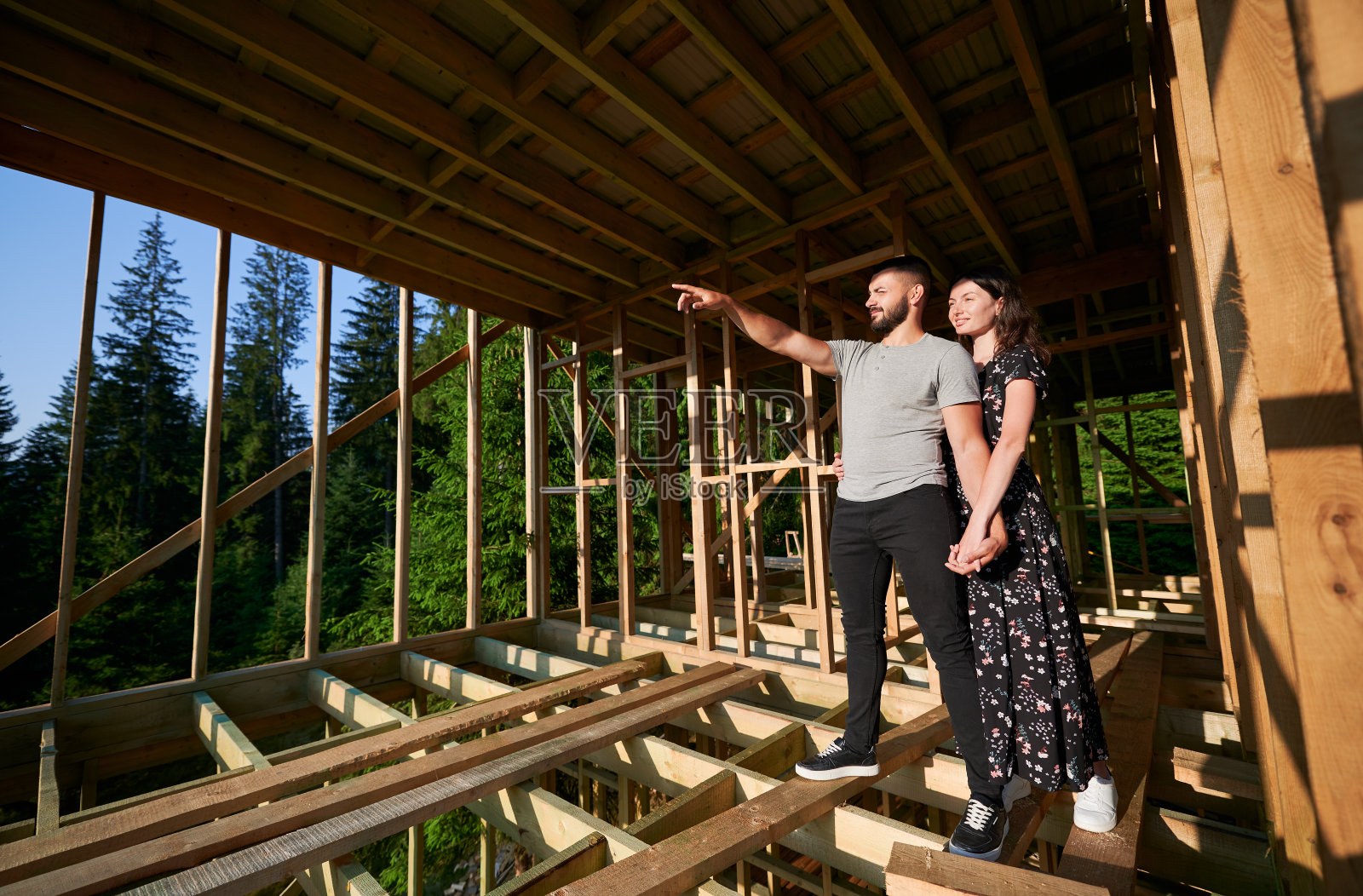 一男一女在森林附近的山上检查他们未来的木结构房子。照片摄影图片