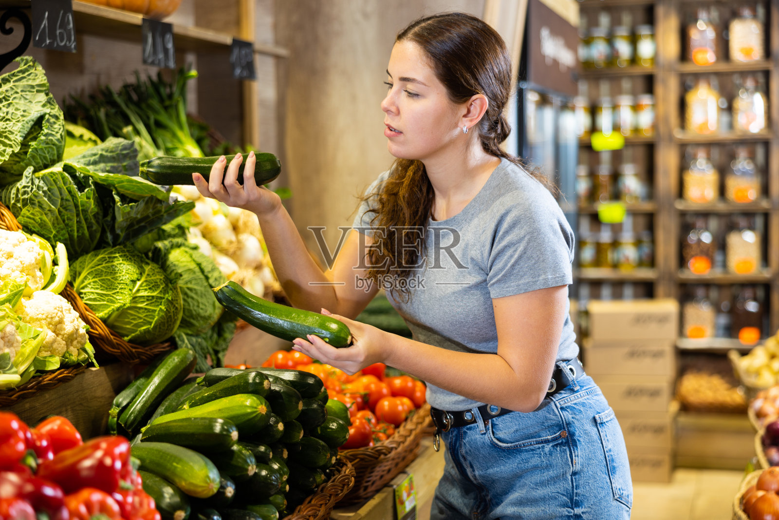 一名妇女在超市的水果和蔬菜区挑选要买的西葫芦照片摄影图片