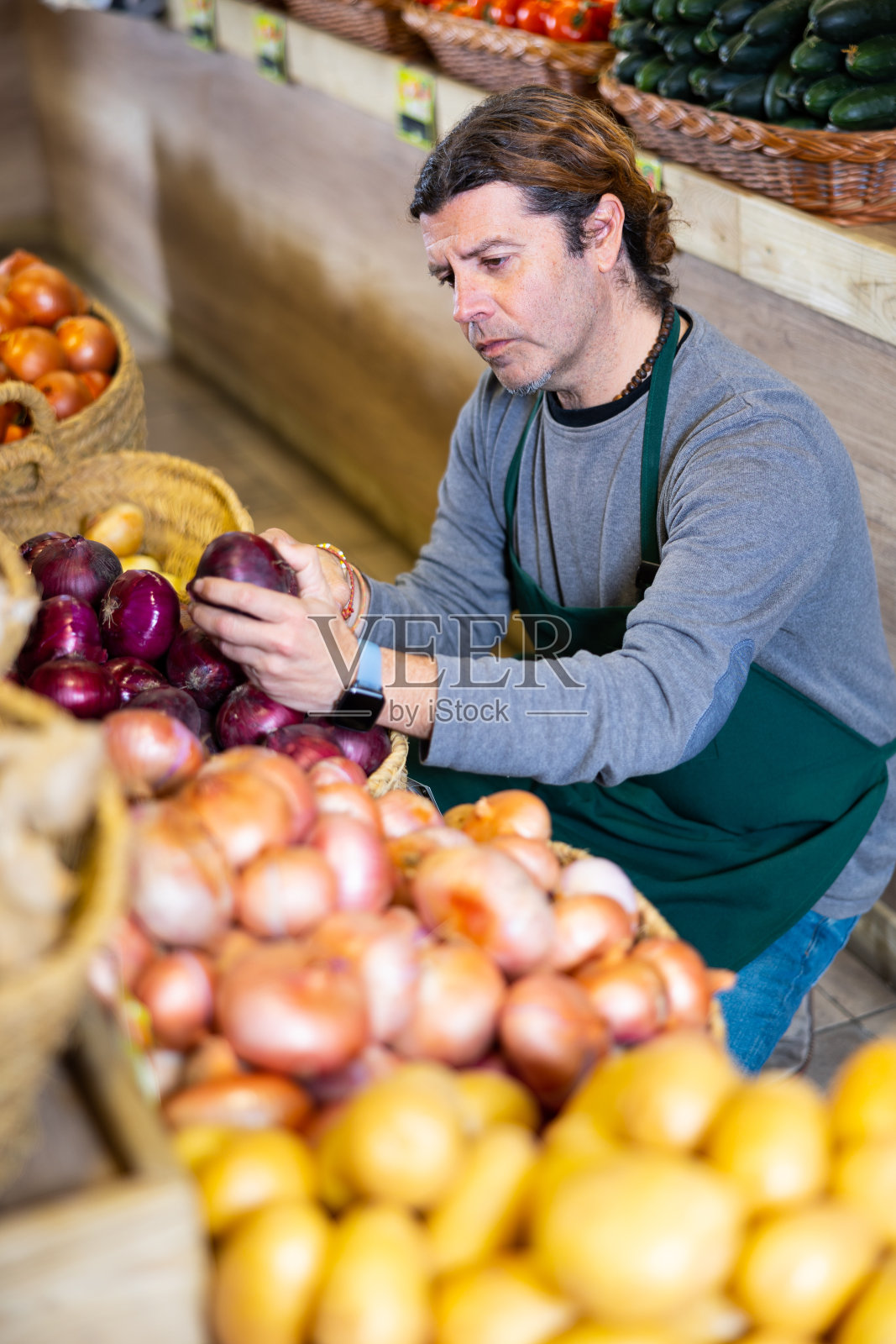 在水果和蔬菜摊位附近卖红洋葱的男售货员照片摄影图片