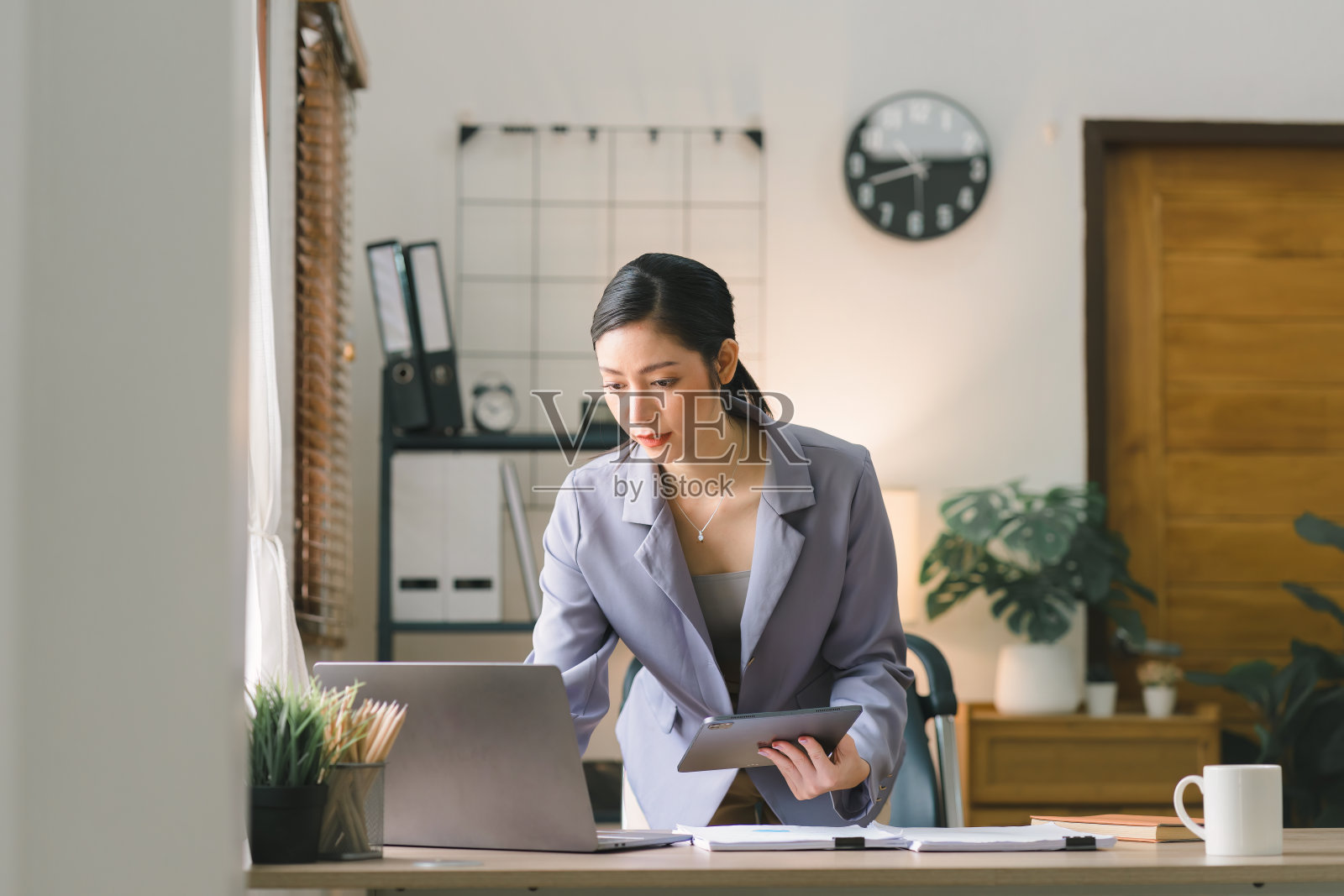 一位千禧一代的年轻女企业家在家庭办公室用数字平板电脑远程工作，这是远程工作概念的一个例证。照片摄影图片