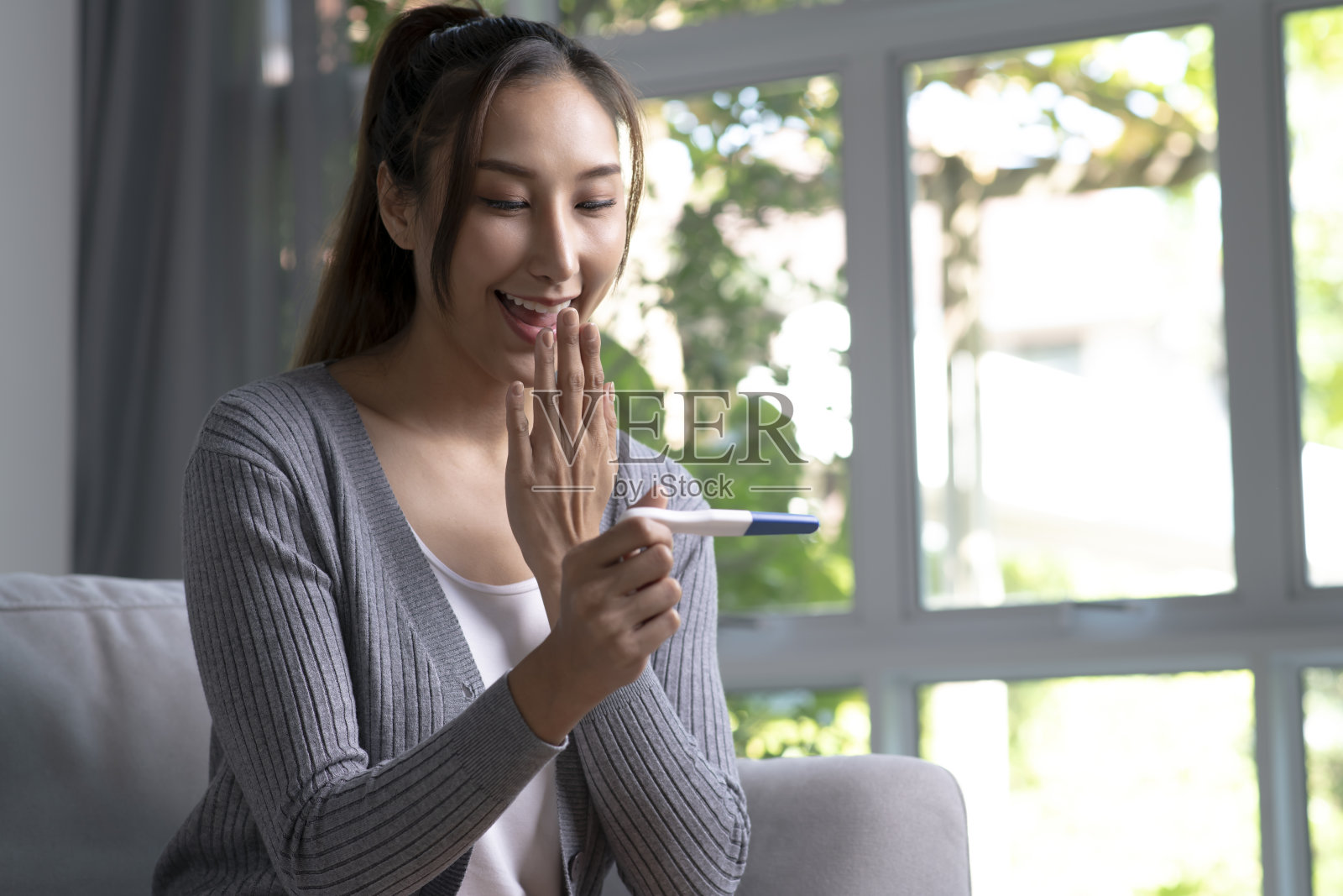 快乐的年轻亚洲女人拿着验孕棒照片摄影图片