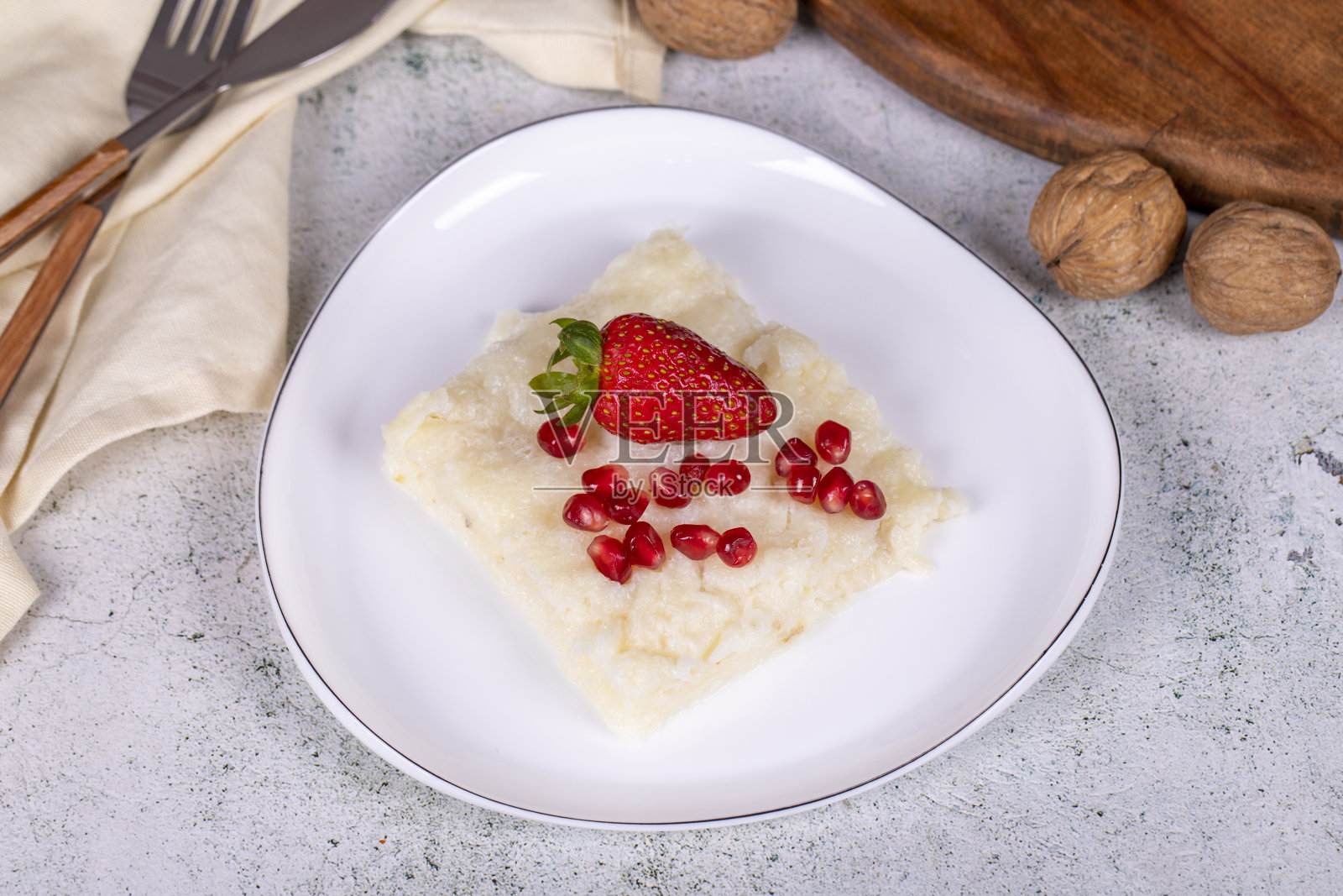 Gullac甜点。传统的斋月甜点。盘子里有石榴和草莓的古拉克甜点照片摄影图片