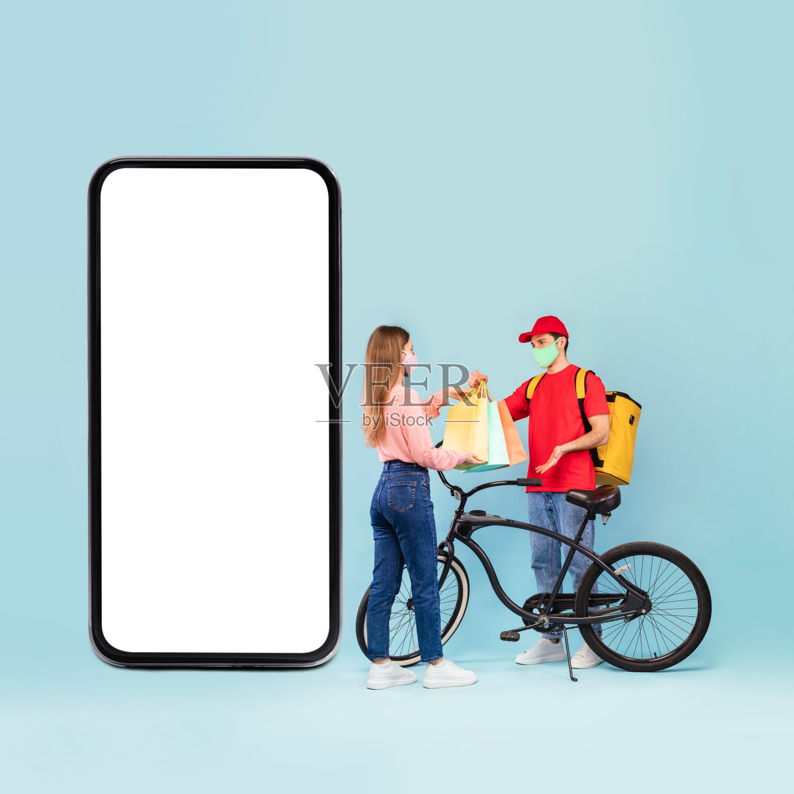 快递员在智能手机旁给女士送购物袋，工作室照片摄影图片