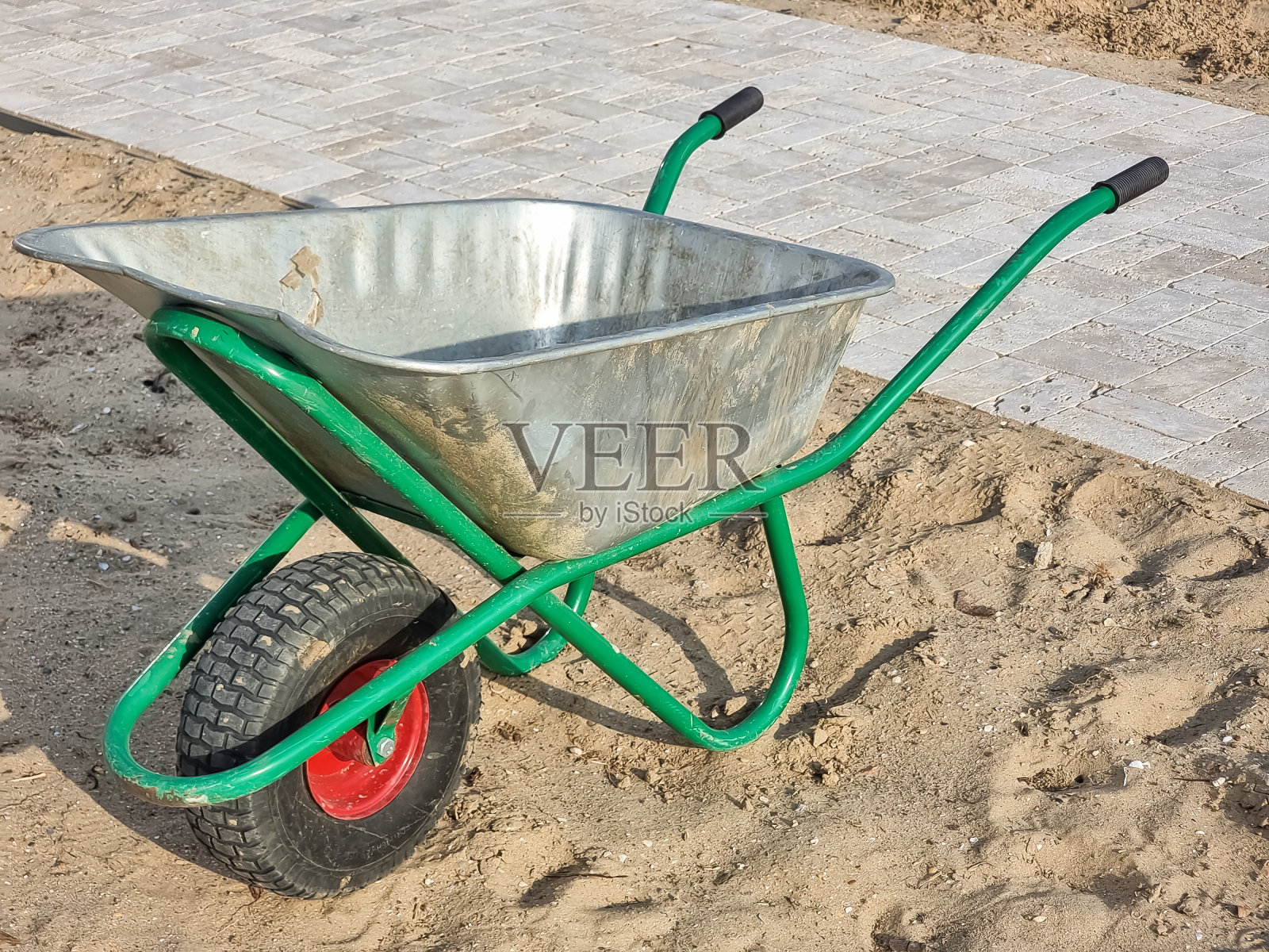 金属花园手推车在花园里。园林作品，在部分花园中有花。农业和园艺的概念。春天在公园的花坛和手推车上种植幼苗照片摄影图片