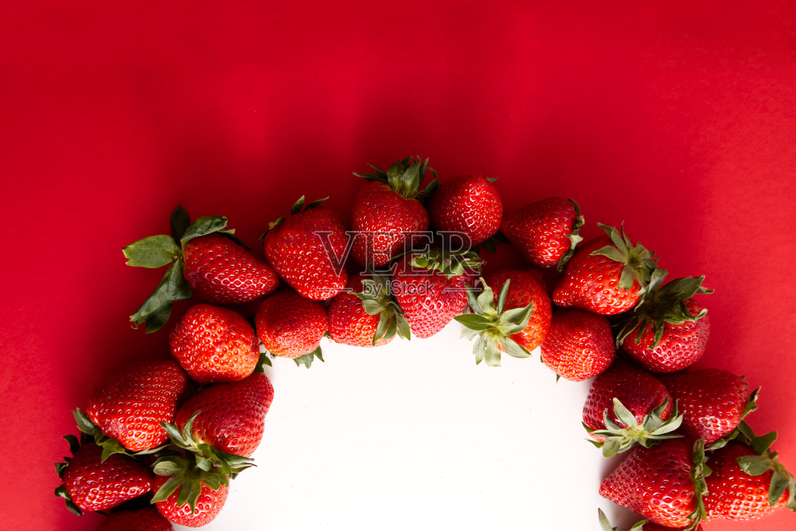 熟草莓特写，在红色背景上呈弧形排列照片摄影图片