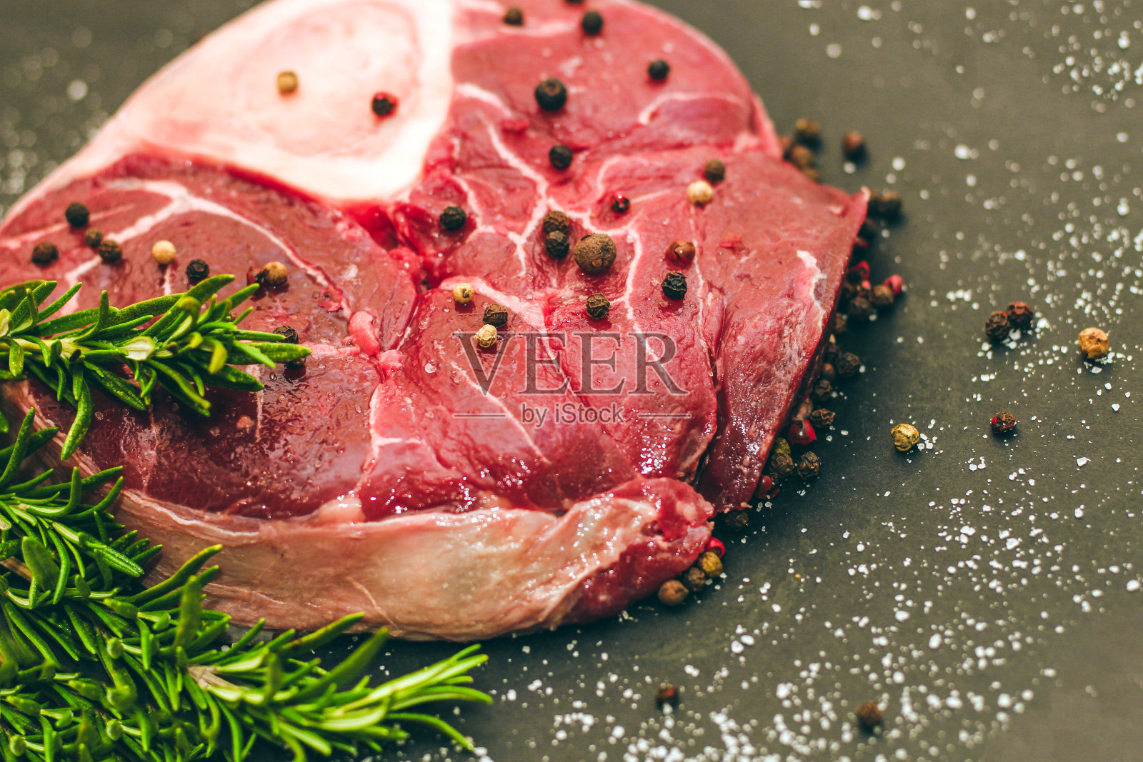 一块新鲜的肉，大牛排上的骨头，黑色背景上的迷迭香照片摄影图片