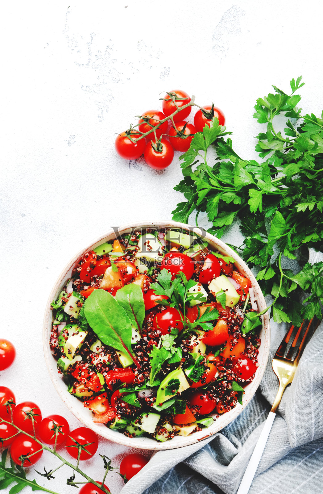 藜麦塔博勒沙拉配红圣女果，橙辣椒粉，鳄梨，黄瓜和欧芹。传统的中东和阿拉伯菜。白色桌面背景，俯视图照片摄影图片