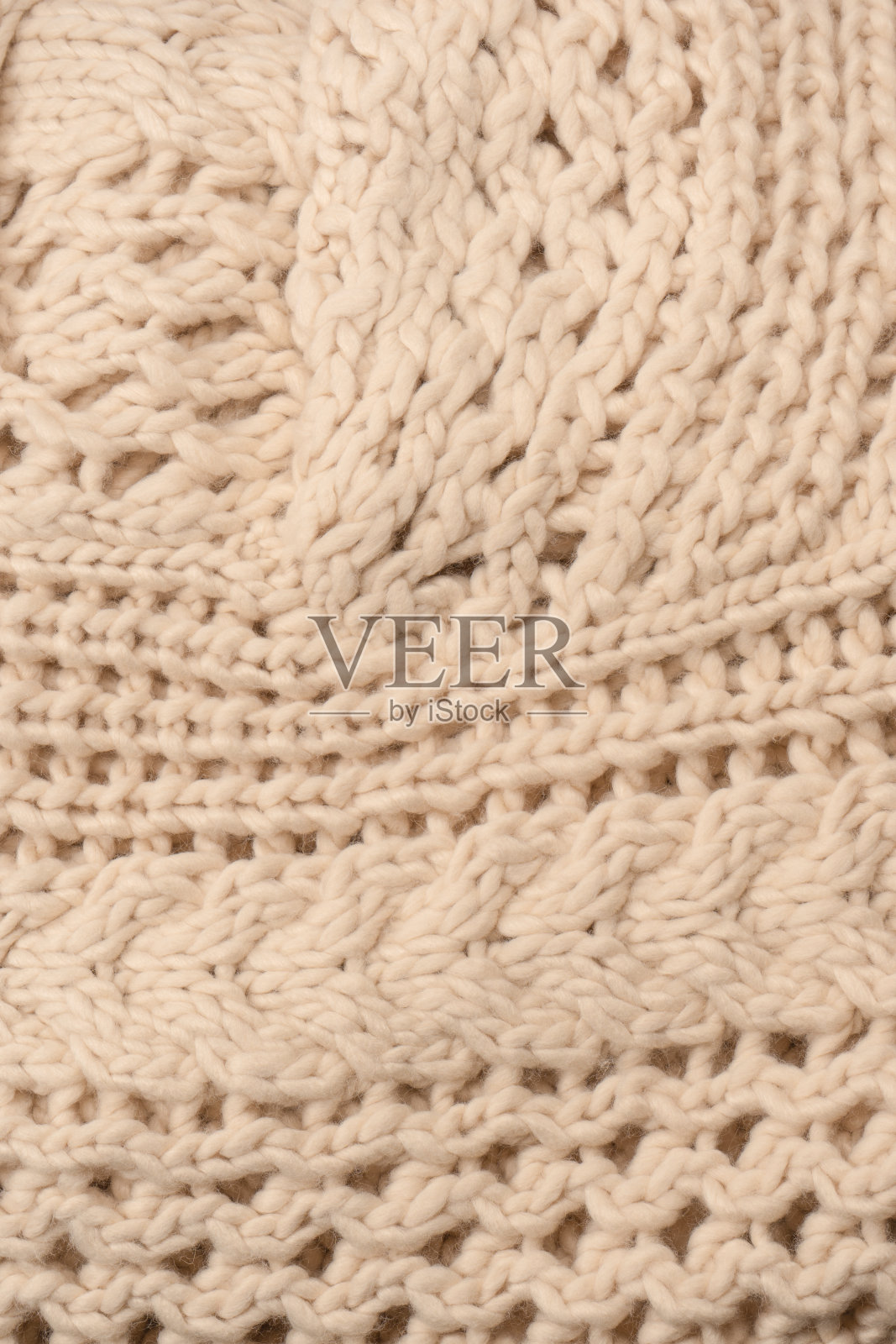 用白羊毛织成的米色针织物碎片。照片摄影图片