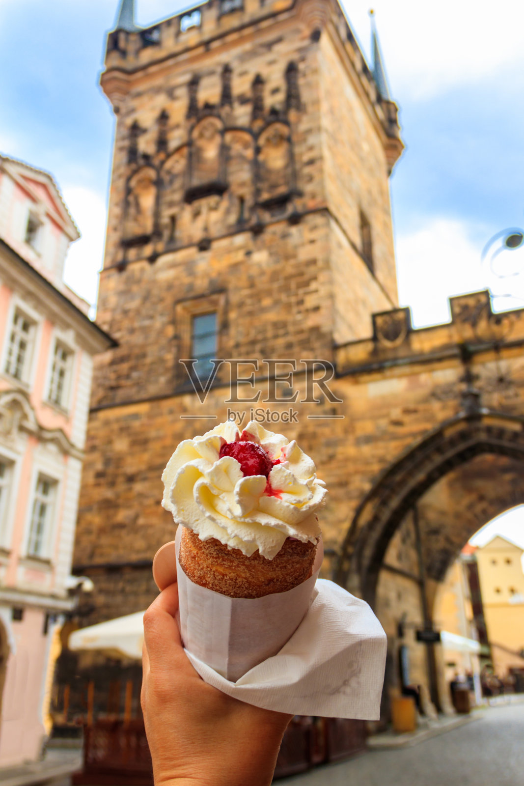 在捷克布拉格著名的查理大桥背景上，女性手拿着捷克传统的奶油蛋糕照片摄影图片