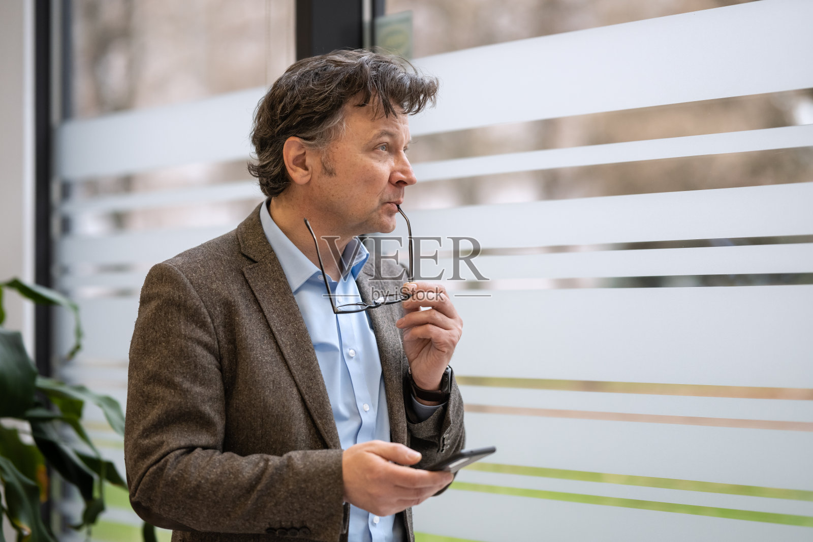 窗边手持电话的商务人士肖像照片摄影图片