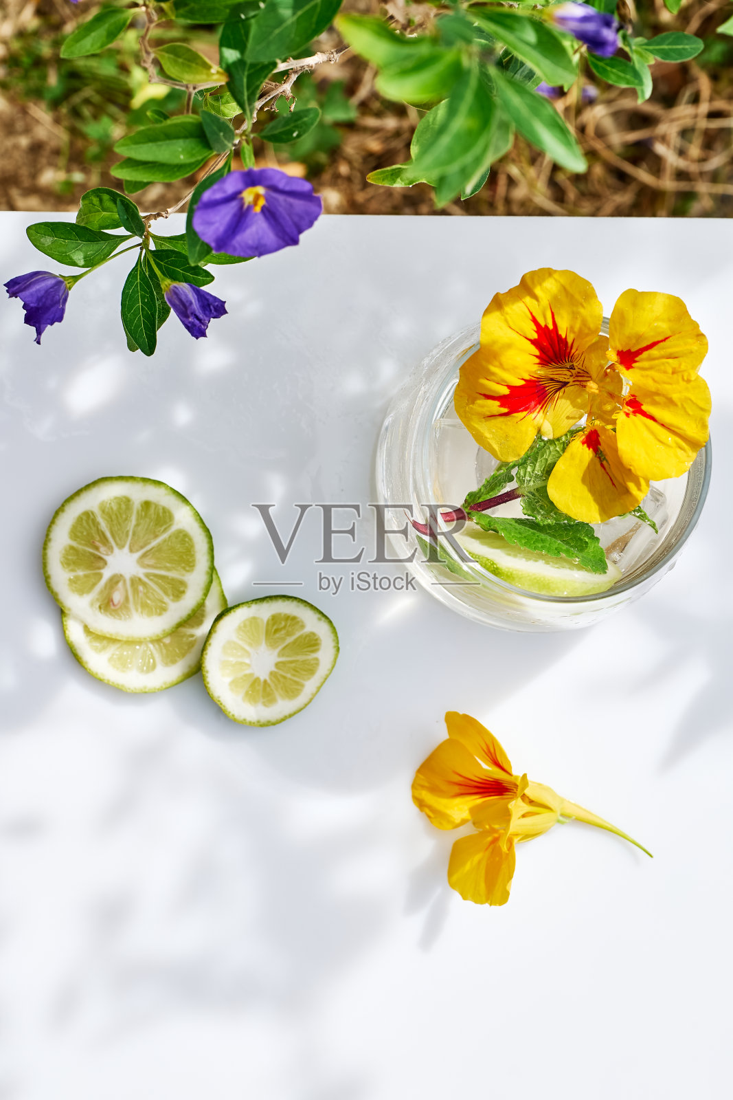 冰柠檬水，可食用的旱金莲花，酸橙和薄荷叶。清凉的夏日饮品。健康的有机夏季苏打饮料。排毒水。不含酒精的鸡尾酒。照片摄影图片