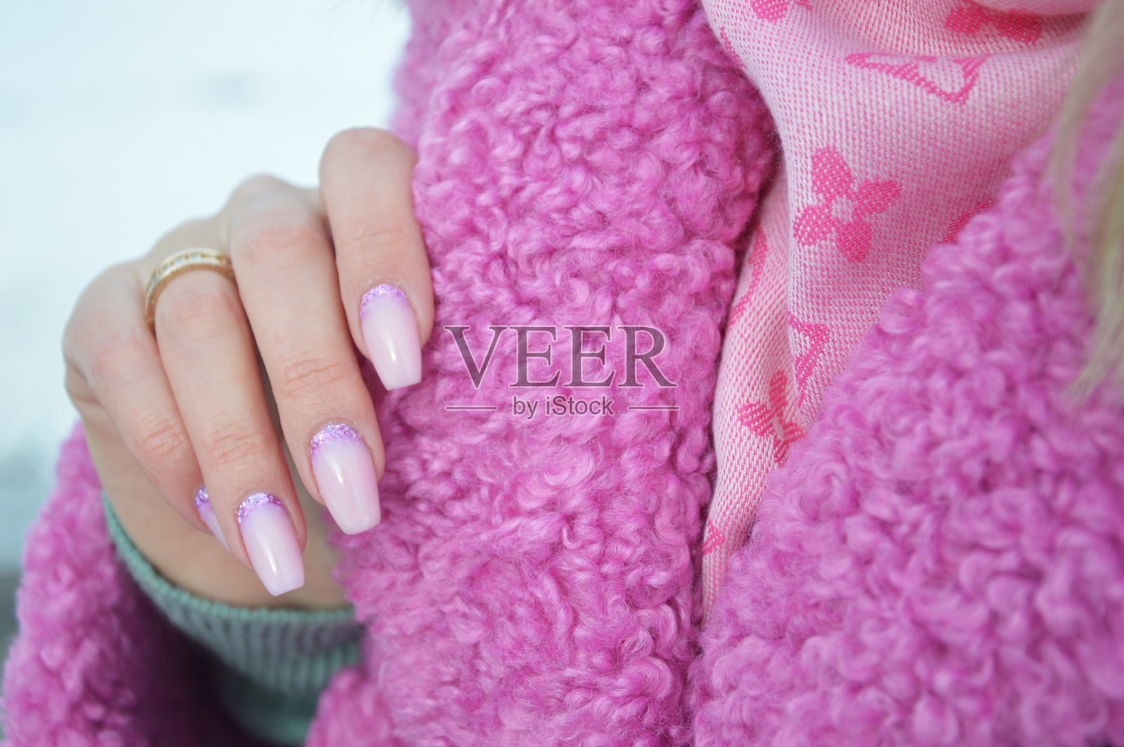 一个有着美丽指甲的女人的手搭在亮粉色外套的领子上。虫胶。冬季美甲设计思路。照片摄影图片