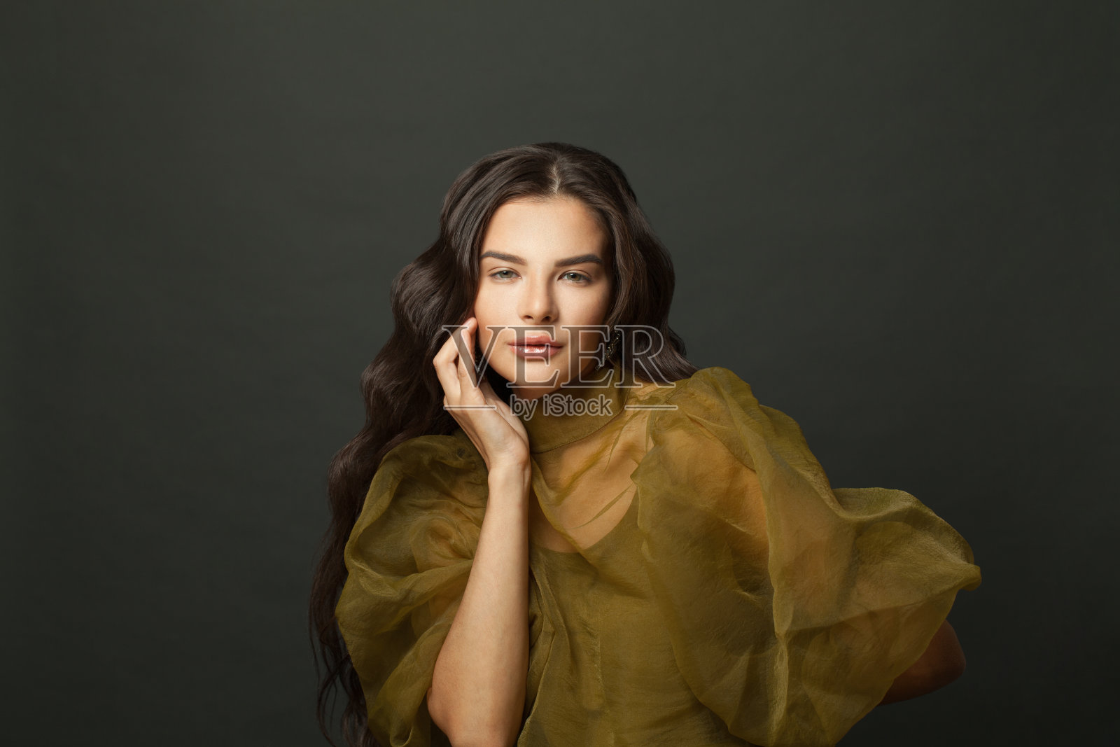 完美的黑发女人在绿色的连衣裙对黑色工作室墙壁背景照片摄影图片