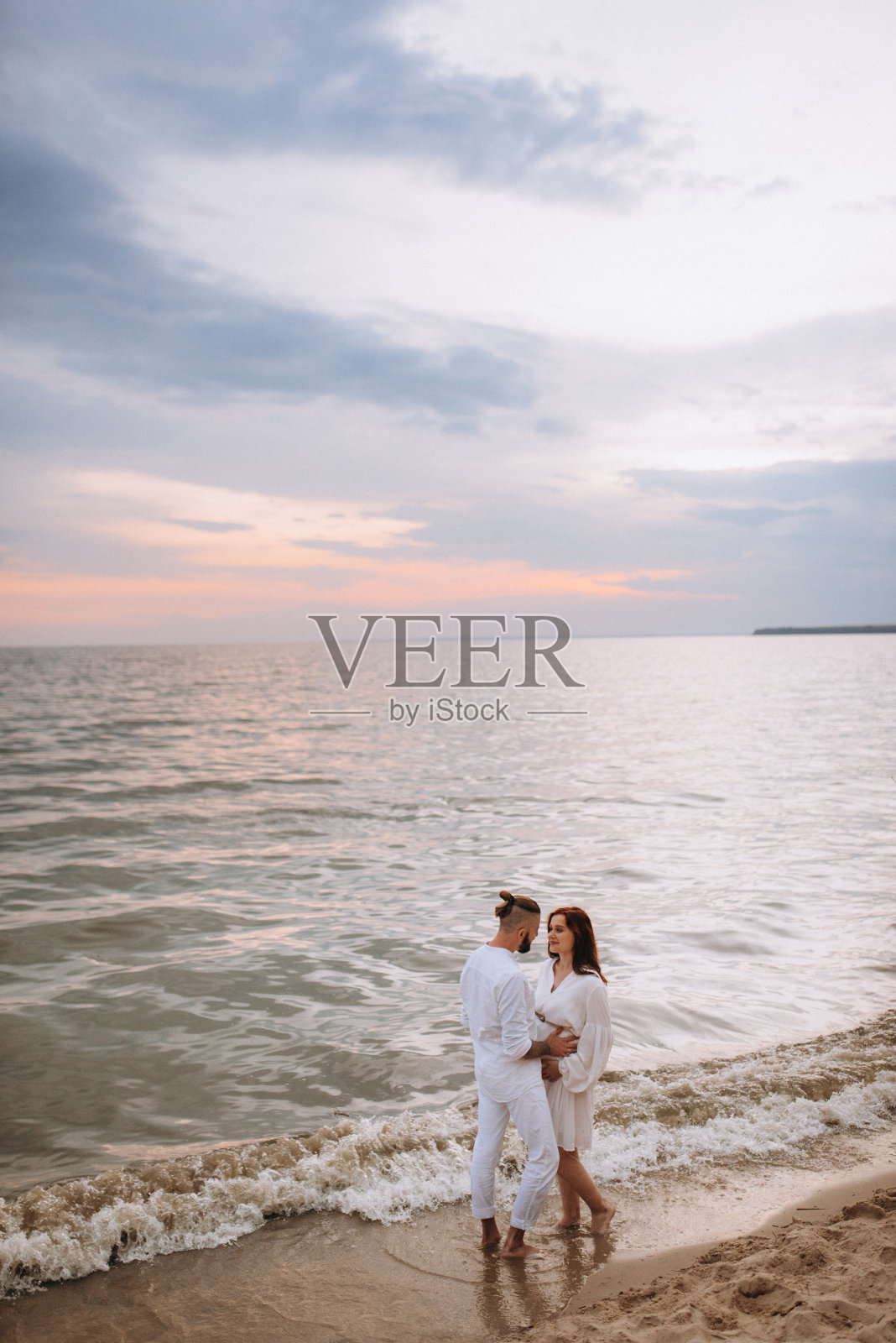 一个男人和一个穿白衣的女孩在海边照片摄影图片