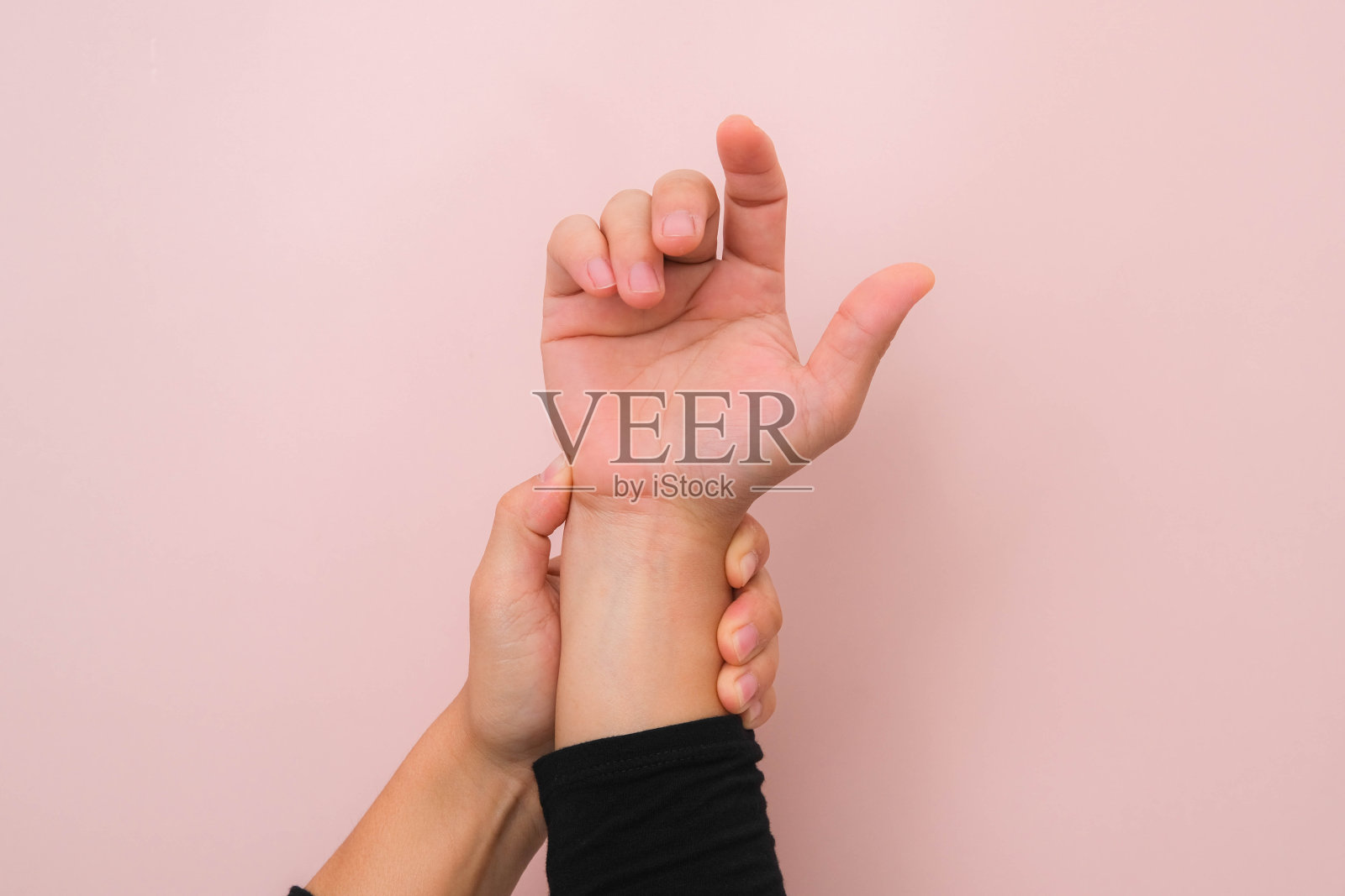 女性的手握住她疼痛的手腕的特写，从关节炎或腕管综合征(CST)中分离出粉红色的背景。医疗保健理念。照片摄影图片