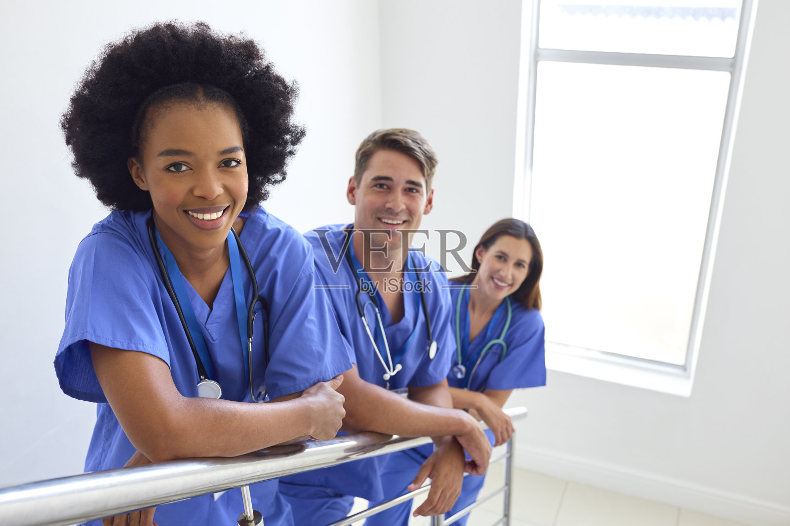 穿着消毒服站在医院楼梯上的多文化医疗团队画像照片摄影图片