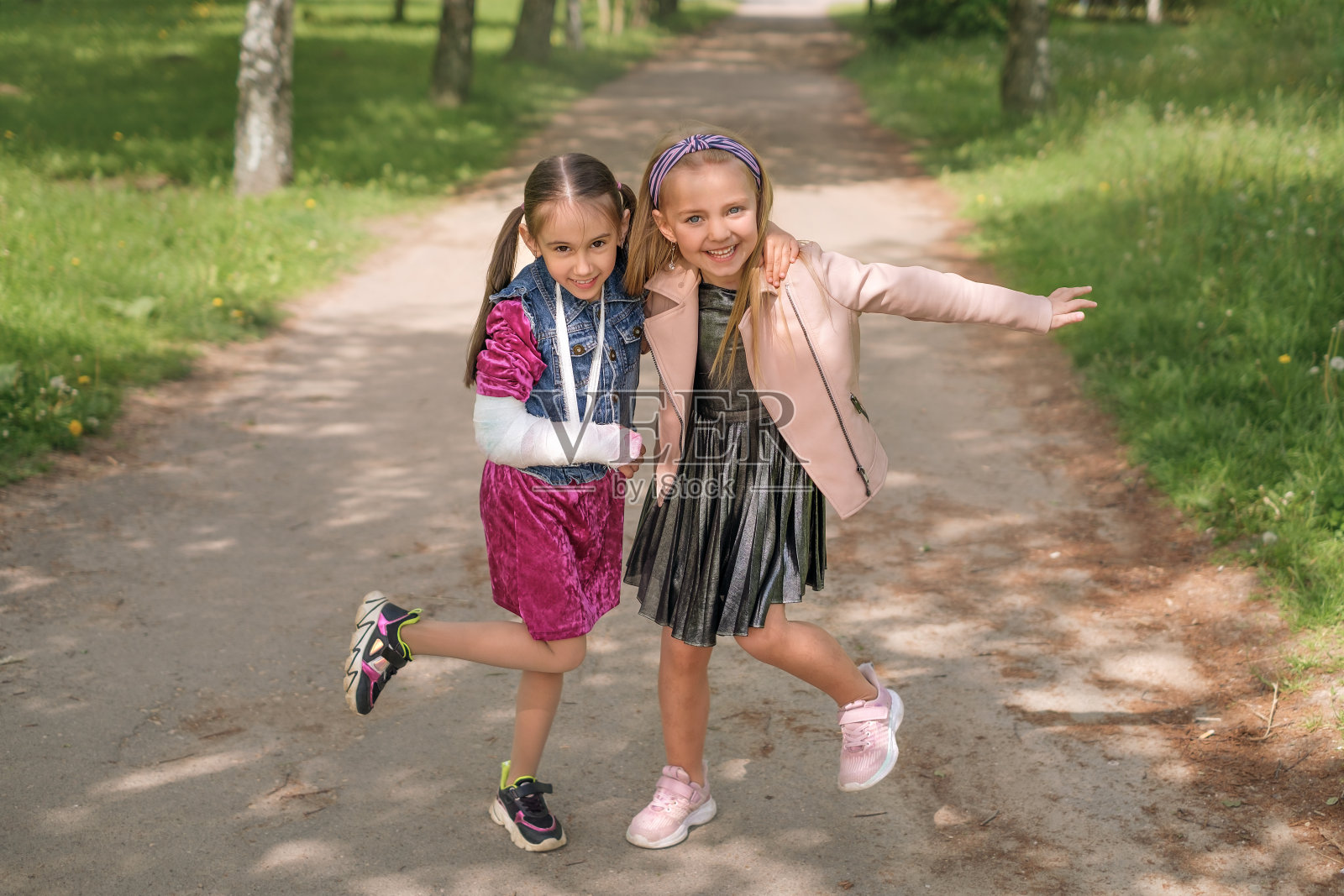 手腕骨折，手臂上打了石膏的女孩开心地笑着拥抱朋友照片摄影图片