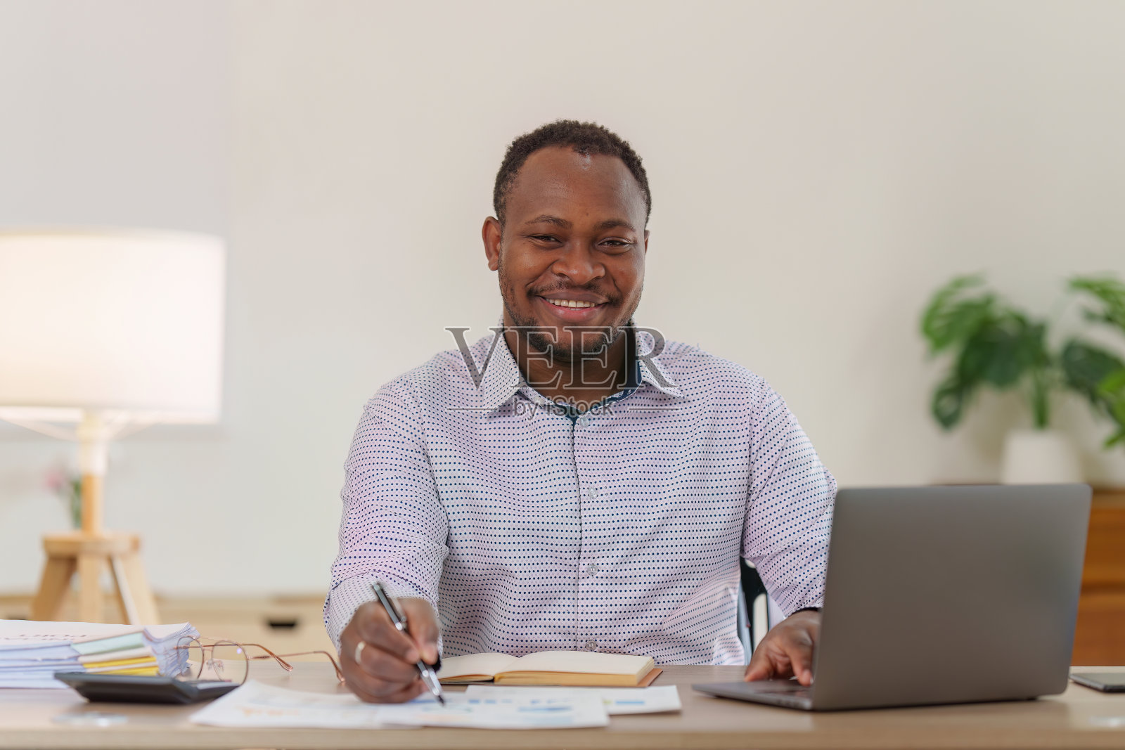 微笑的美国非洲银行家或会计师做财务报告，研究年度数据，分析利润。会计检查财务状况照片摄影图片