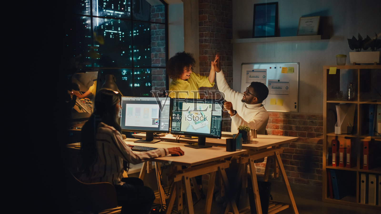 艺术总监和平面设计师讨论商业伙伴的营销活动。成功的男女同事互相击掌。小创意团队在办公室一起工作。照片摄影图片