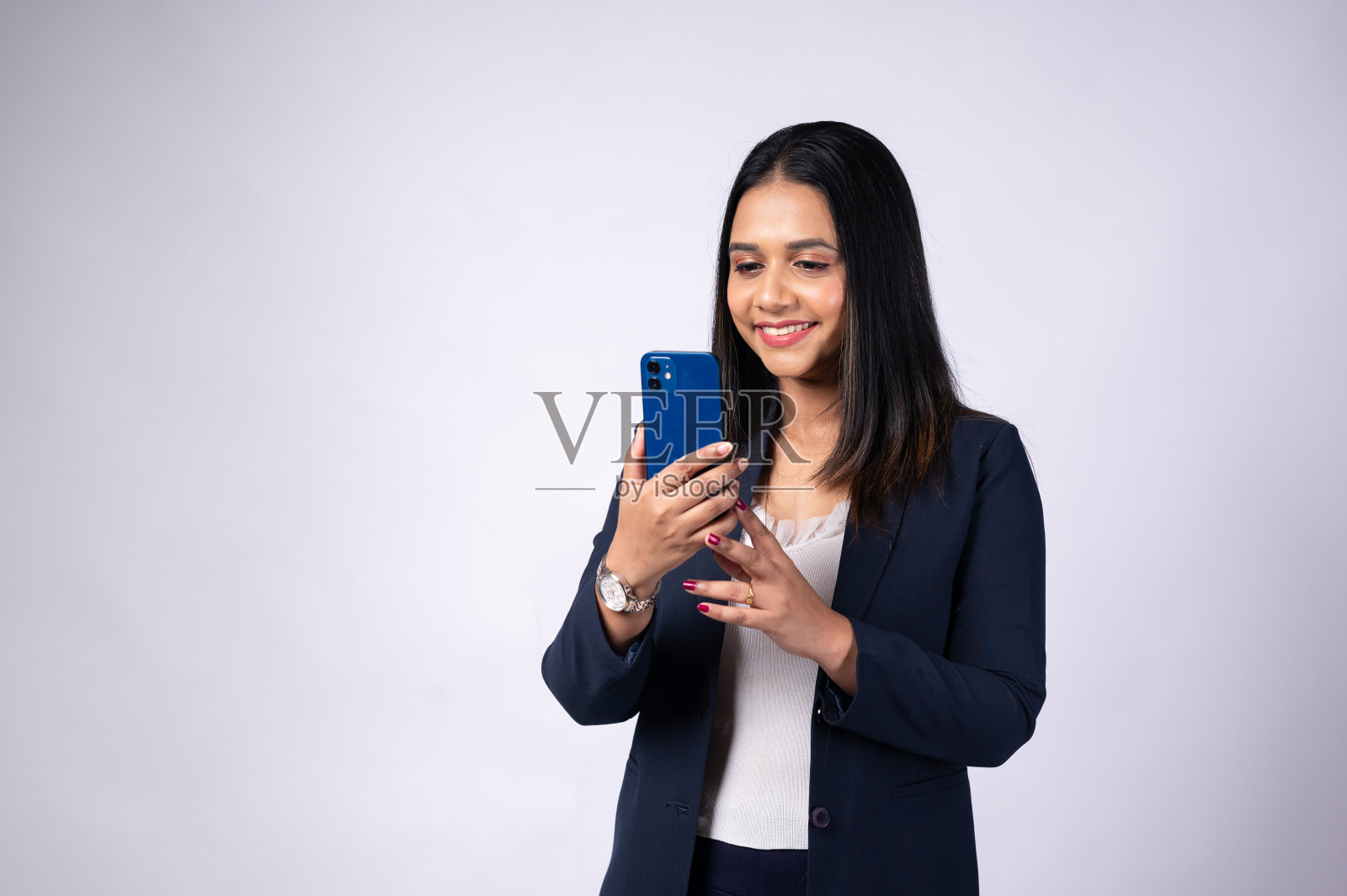 用智能手机拍摄的短发年轻女性的肖像，在白色背景上的工作室拍摄照片摄影图片