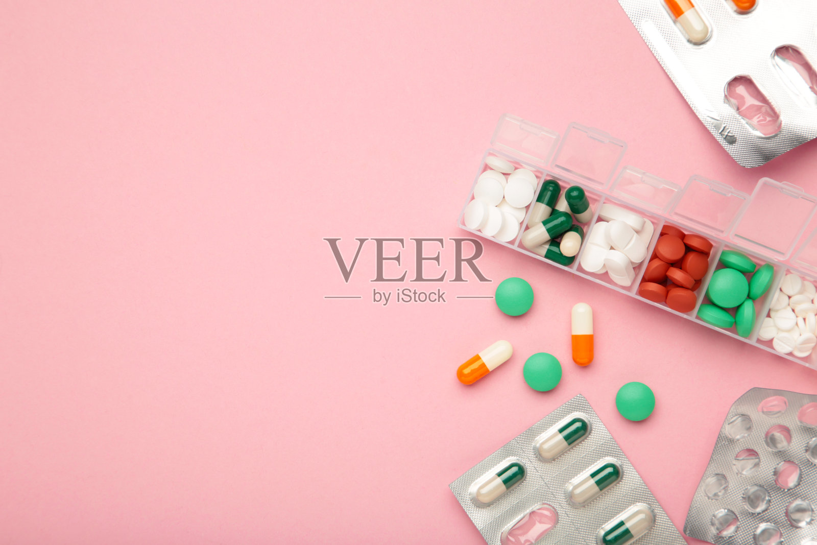 粉红色背景的装有药物和营养补充剂的日常药丸盒。文本空间照片摄影图片