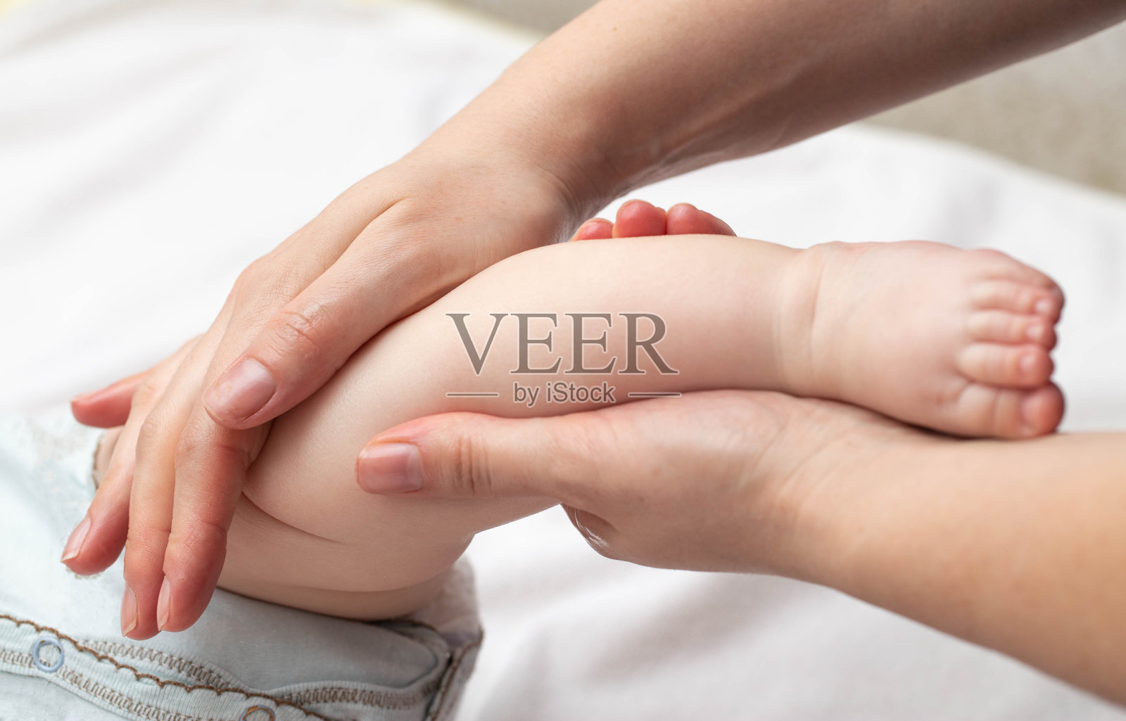 妈妈在宝宝的皮肤上涂上一层含油的保湿霜，这样身体就不会变得干燥。新生儿的卫生和皮肤护理。照片摄影图片