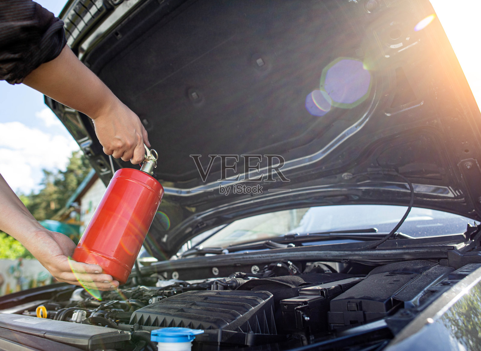汽车司机将粉末灭火器对准着火和冒烟的汽车发动机舱。汽车起火，背景。电气短路照片摄影图片