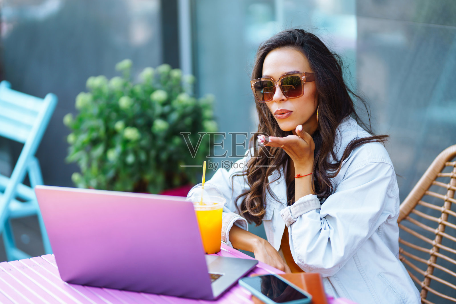 年轻而开朗的女人在阳台上用Skype聊天，用网络摄像头聊天，开视频会议。照片摄影图片