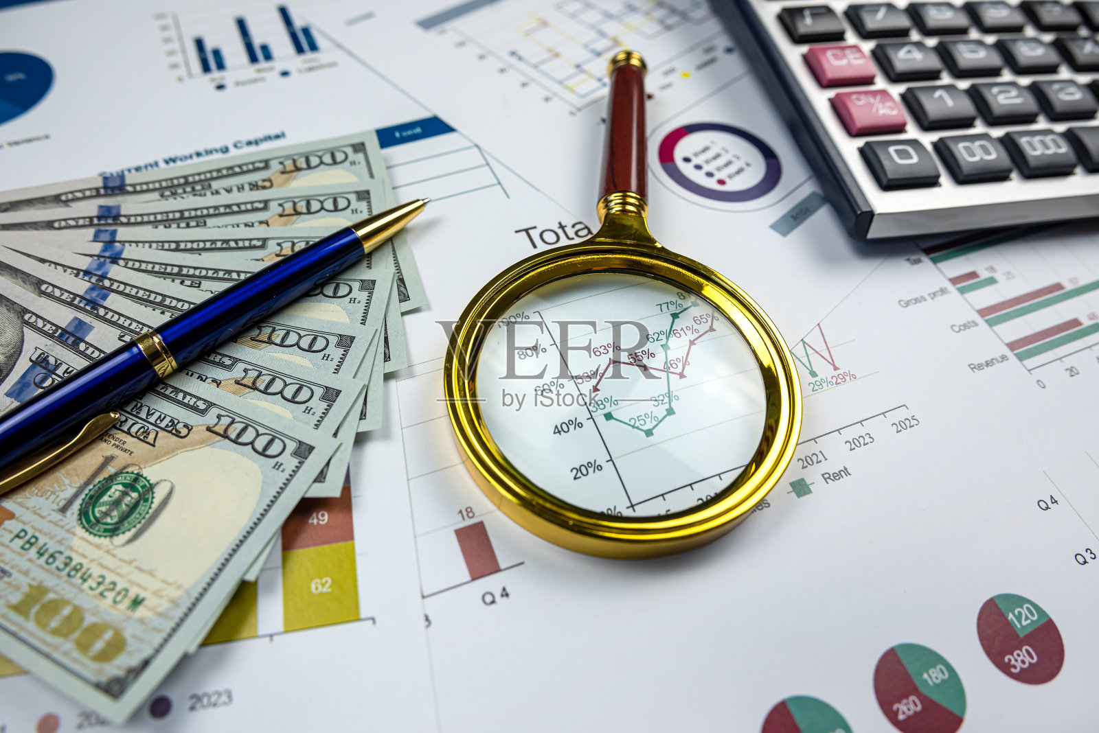 商务图表纸笔计算器美元放大镜在办公桌上照片摄影图片