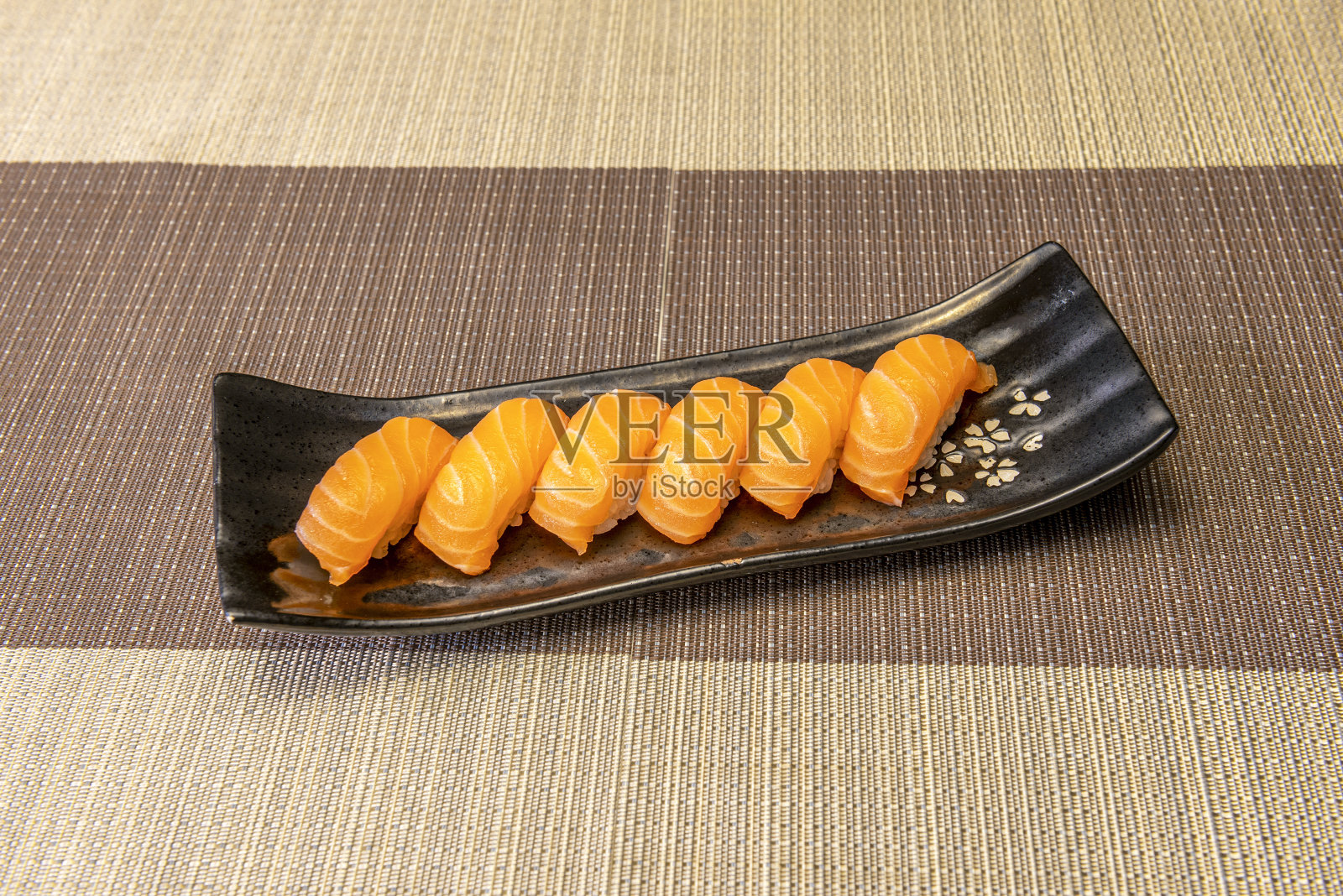 六份超级开胃的挪威三文鱼寿司寿司，装在带有亚洲花卉图案的黑色瓷盘上照片摄影图片