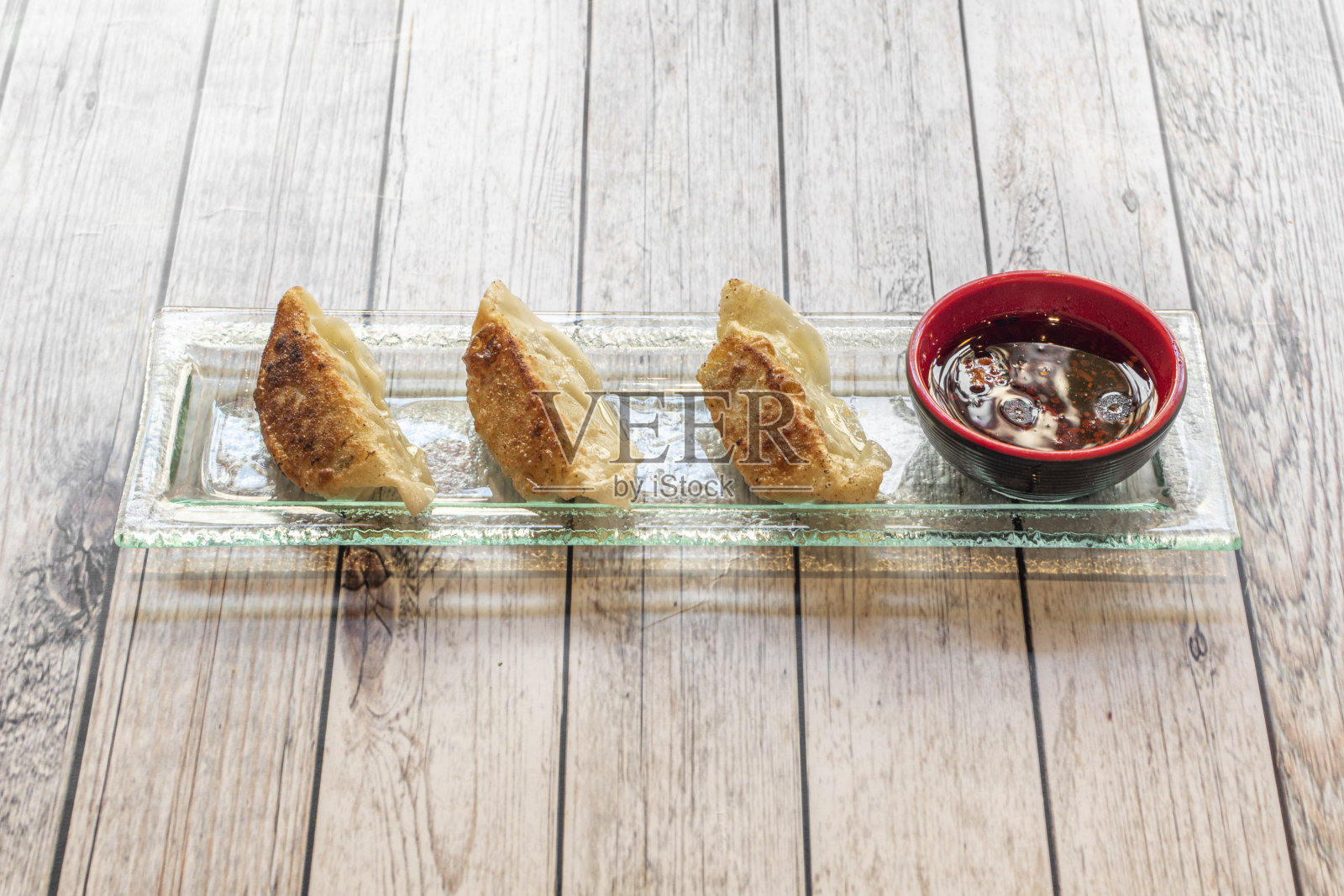 玻璃托盘上放着日本饺子，日式饺子，旁边放着一罐酱油照片摄影图片