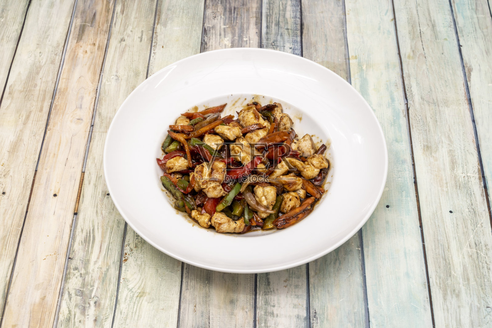 一盘用酱油、红椒、青椒、洋葱和胡萝卜炒鸡照片摄影图片