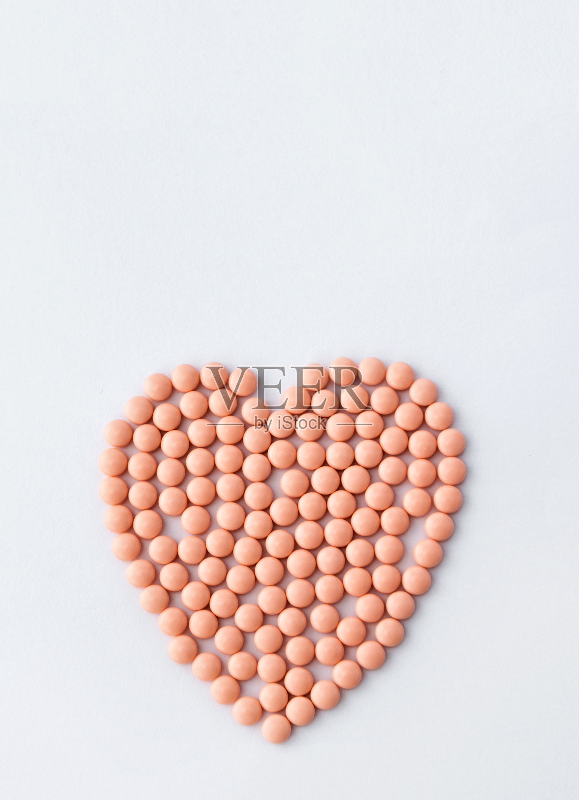 白色背景上心形的粉色药丸。维生素和健康皮肤的补品。网上药店。制药行业。爱的治疗方法。高质量的照片。照片摄影图片