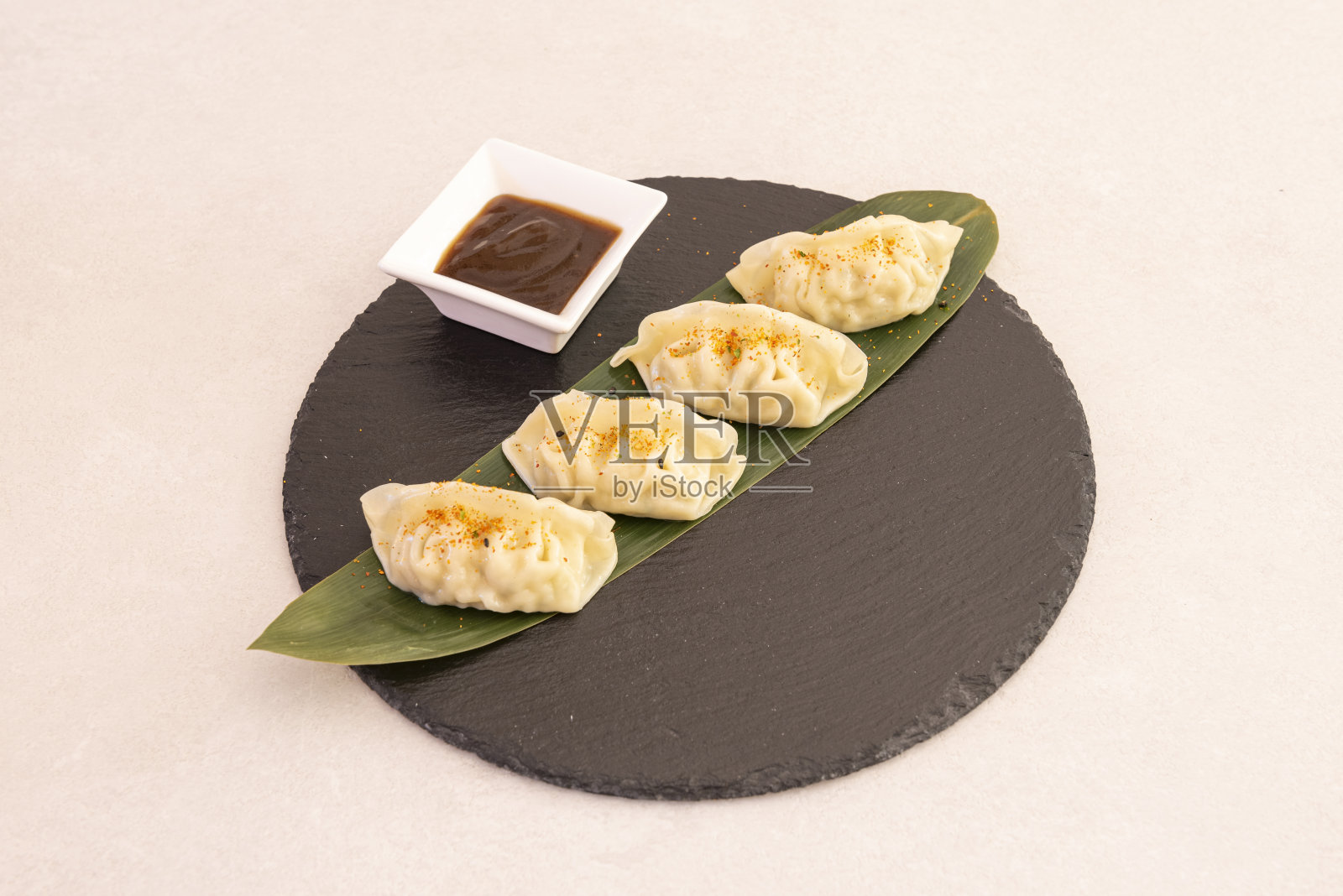 中国饺子，点心，蒸酱油在一个圆形的黑色石板板和香蕉叶照片摄影图片