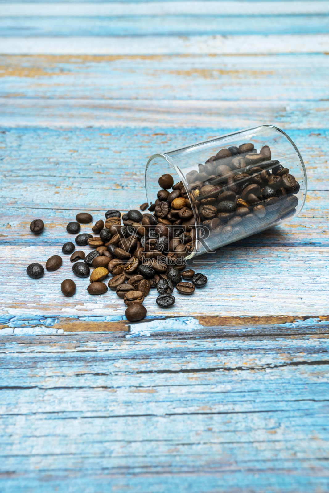 玻璃罐子打翻在一些蓝色的木板上，上面装满了烤过的咖啡豆照片摄影图片