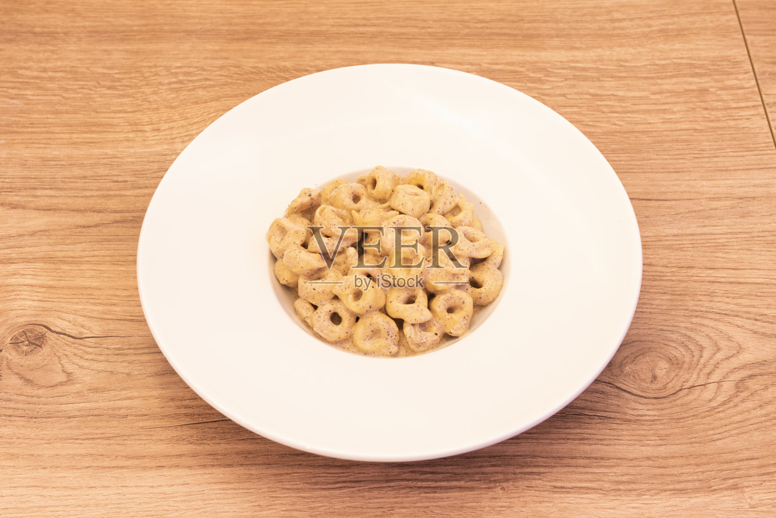 一盘美味的意大利饺子在塔图福酱白色盘子和轻木桌结照片摄影图片