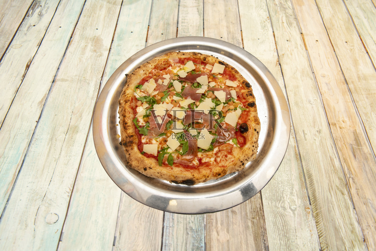 塞拉诺火腿披萨配芝麻菜和帕尔马干酪片，配番茄和细面粉面团照片摄影图片