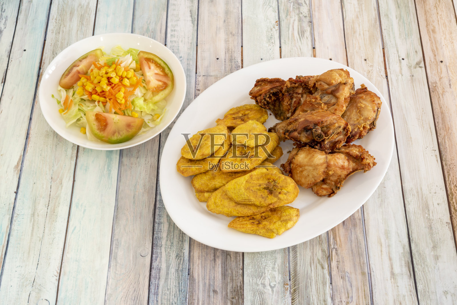 典型的多明尼加菜，凉拌鸡肉配上油炸香蕉片，配上甜玉米、番茄和生菜沙拉照片摄影图片