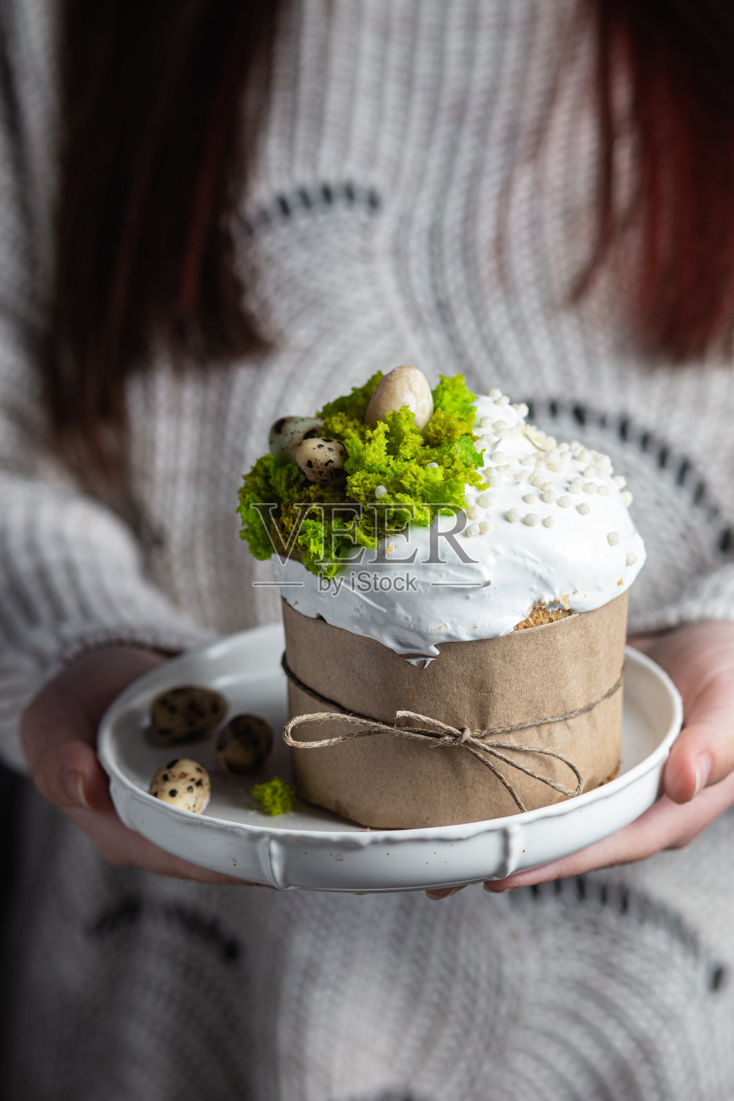 一个女人手里拿着一个复活节蛋糕，盘子里有蛋白霜和装饰照片摄影图片