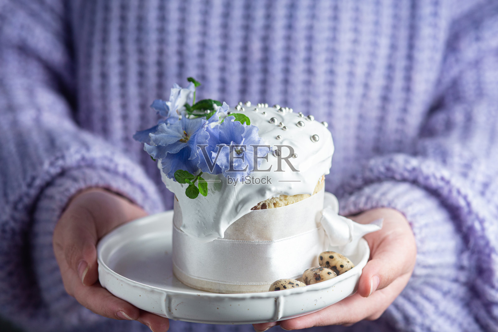 一个女人手里拿着一个复活节蛋糕，盘子里有蛋白霜和装饰照片摄影图片