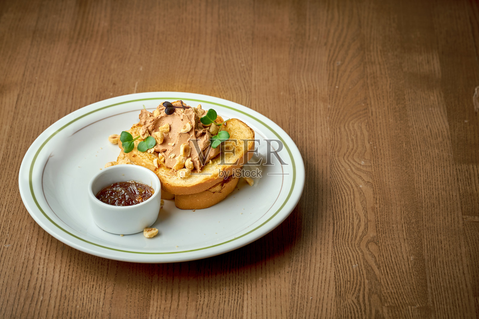 烤面包配肉酱和坚果，放在木制背景的盘子里照片摄影图片