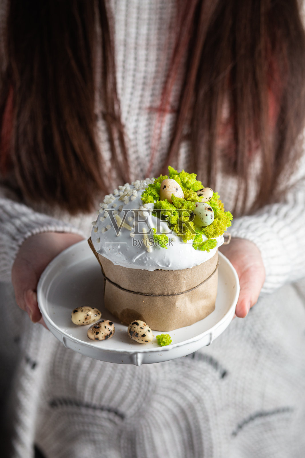 一个女人手里拿着一个复活节蛋糕，盘子里有蛋白霜和装饰照片摄影图片
