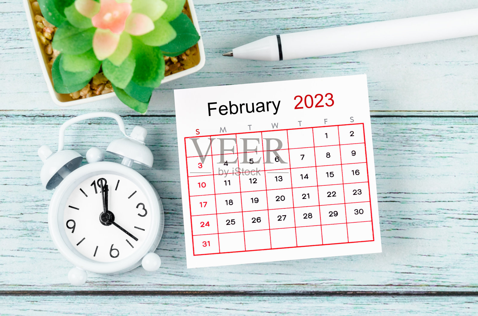 2023年12月日历年和闹钟与笔在蓝色木制背景。照片摄影图片