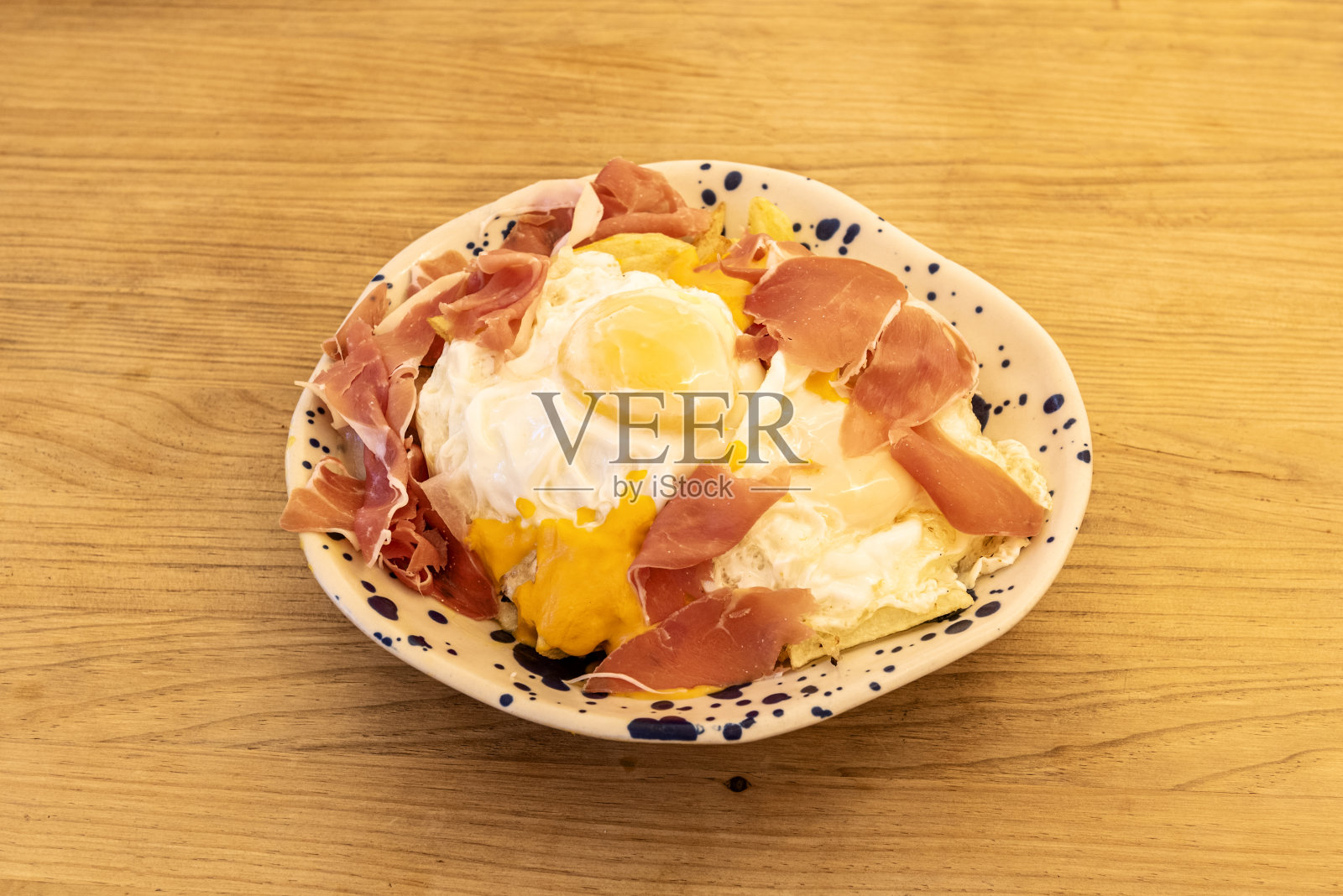 著名的西班牙菜，打碎的鸡蛋配塞拉诺火腿，在黑点的白色碗上分享西班牙小吃的风格照片摄影图片