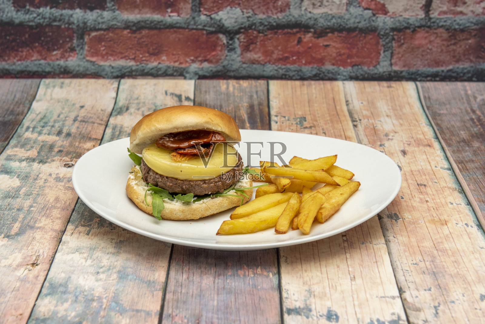 意大利汉堡，上面有芝麻菜、奶酪和脱水番茄，配以自制薯片照片摄影图片