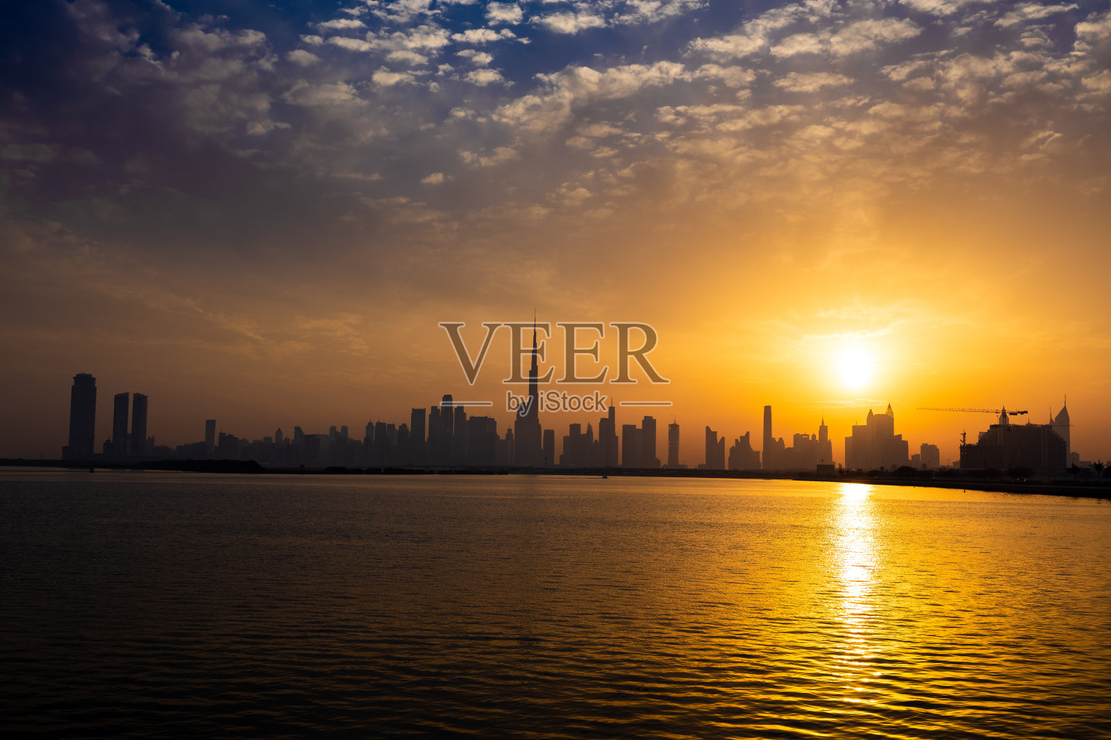 日落时分的迪拜天际线。迪拜的天际线投下长长的阴影，在夜空中形成了一个令人惊叹的剪影。照片摄影图片