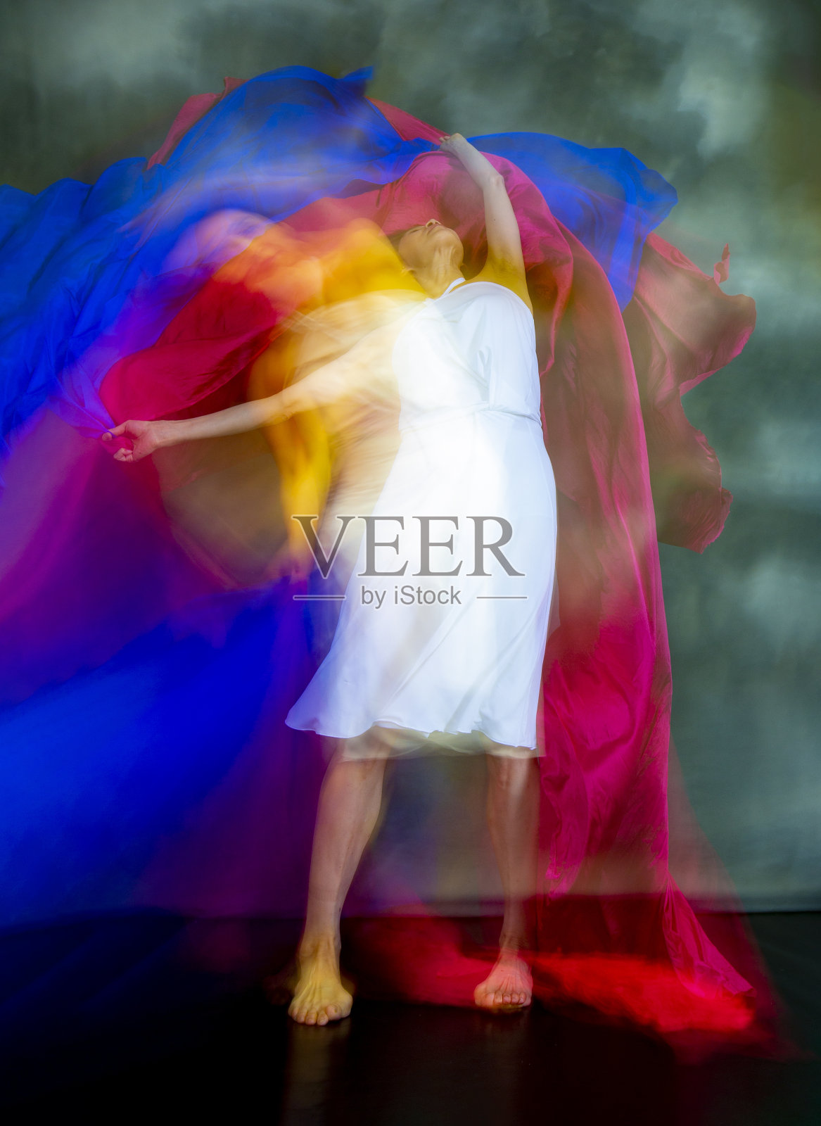 神秘的，模糊的舞蹈照片的成年妇女与彩色织物。照片摄影图片
